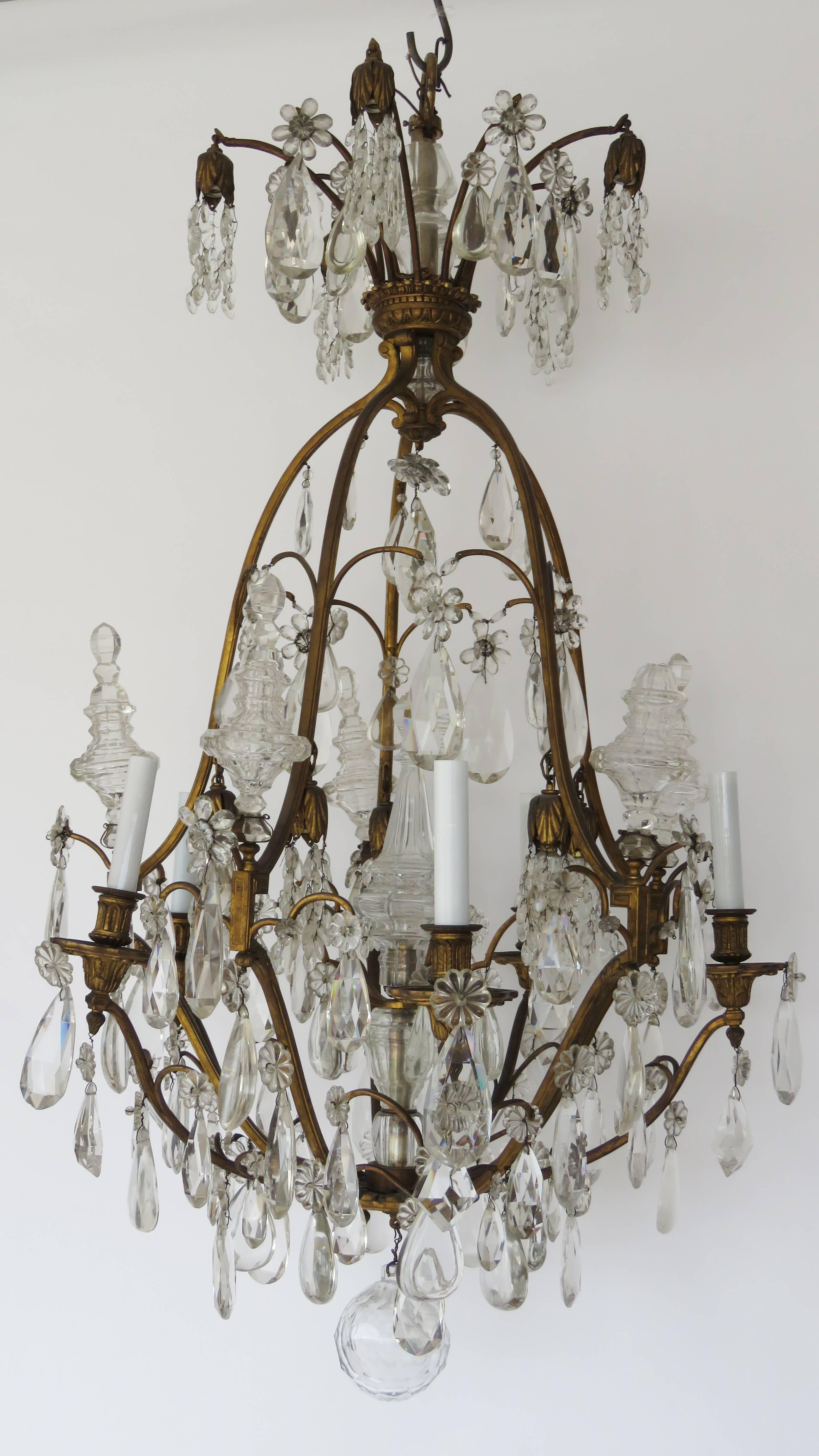 Impressive chandelier with antique finish gilt bronze gilt corona supporting crystal prisms and four fine bronze arms supporting candle lights and hanging crystal prisms and rosette pendants. Central cut-glass sphere. Total number lights: 6+5+5. One