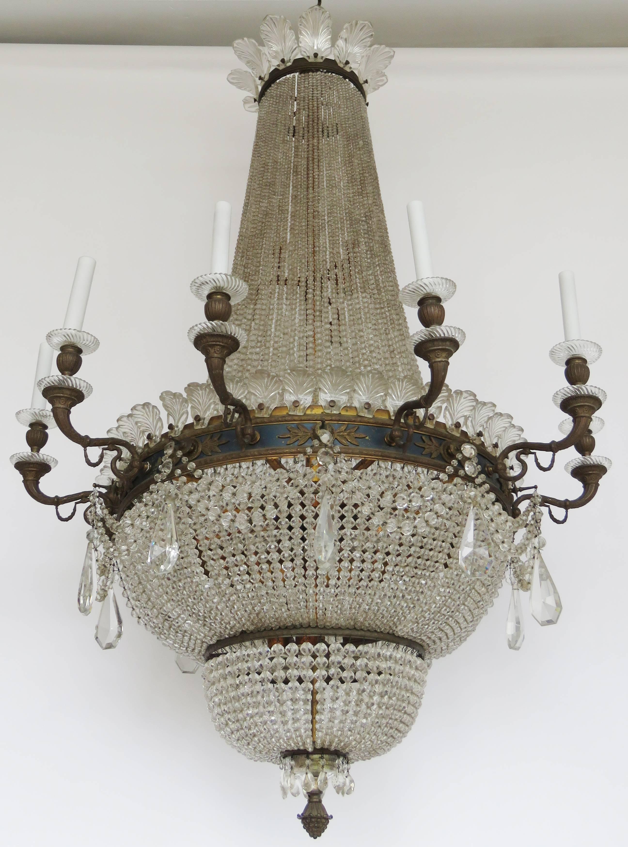 The corona with glass palmettes supports faceted chains falling to a gilt ring issuing candle light arms and glass bobèches above a double basket form.