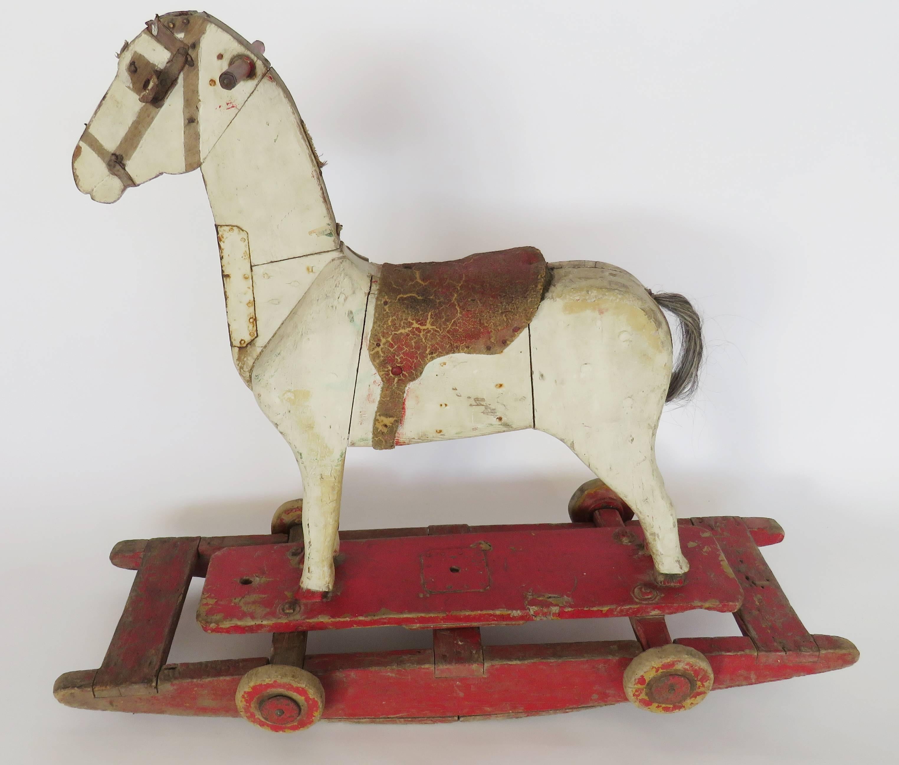 Painted horse with leather saddle mounted on four small wheels, can also be used on the wooden rocker.