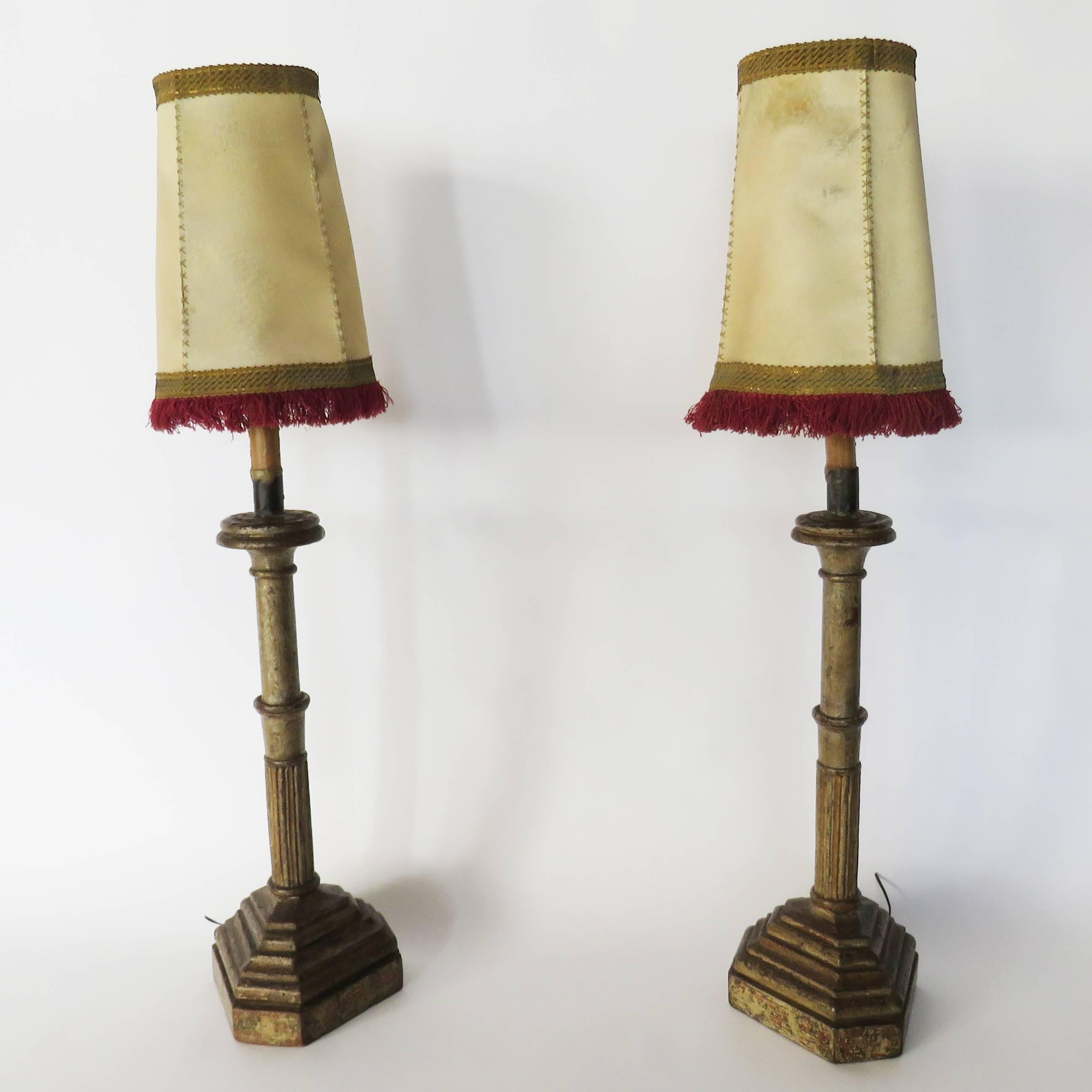 Ringed and fluted wooden standard over a molded tri-form plinth, genuine pigskin shades with cross stitching and ruby fringing. Now drilled and mounted as lamps.

Candlestick size: Height 30 inches to the socket x diameter 8 inches
Shade size: