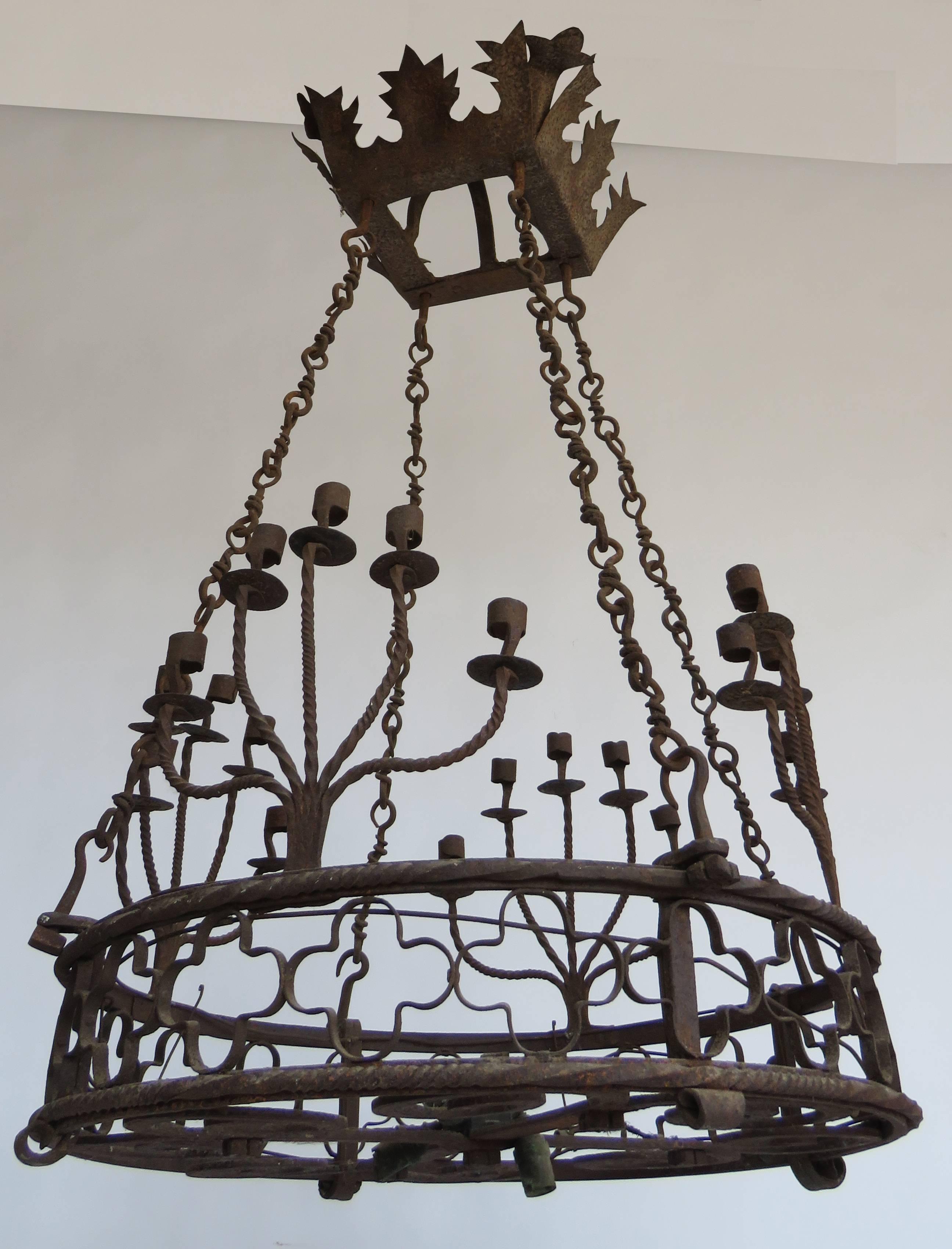 Hand-forged wheel shape iron chandelier decorated with quatrefoils, 4 twisted rod branches with 5 candleholders.