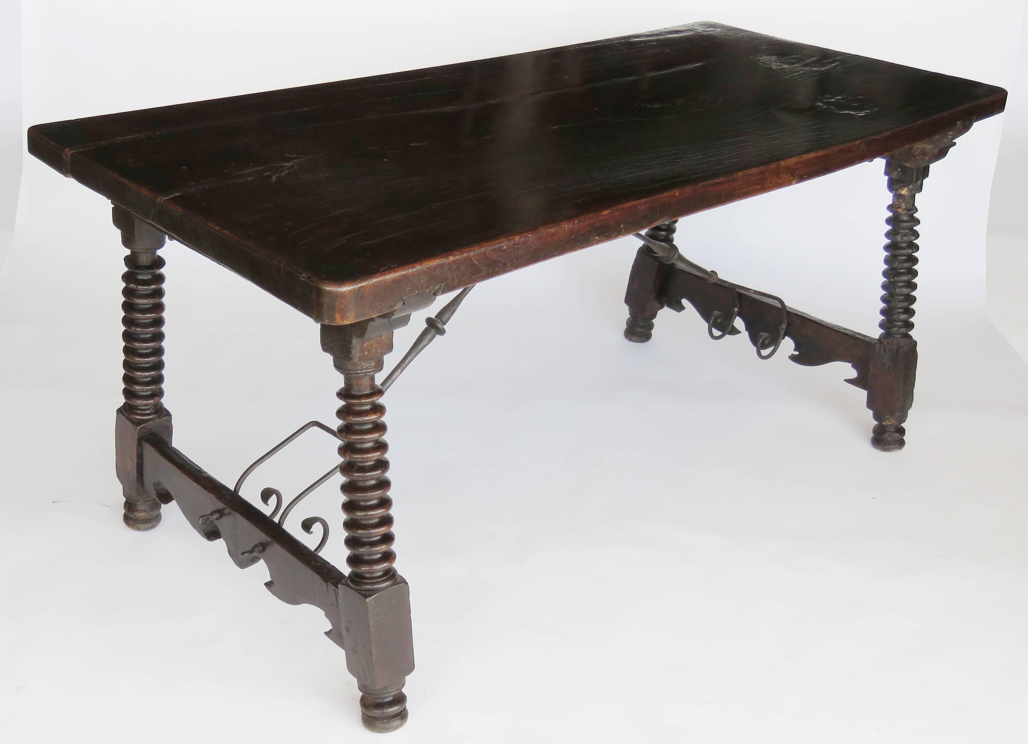 Rectangular thick single plank top raised on ring turned legs joined by undulating stretchers secured by later wrought iron supports ending on bun feet.

Exceptional patina.