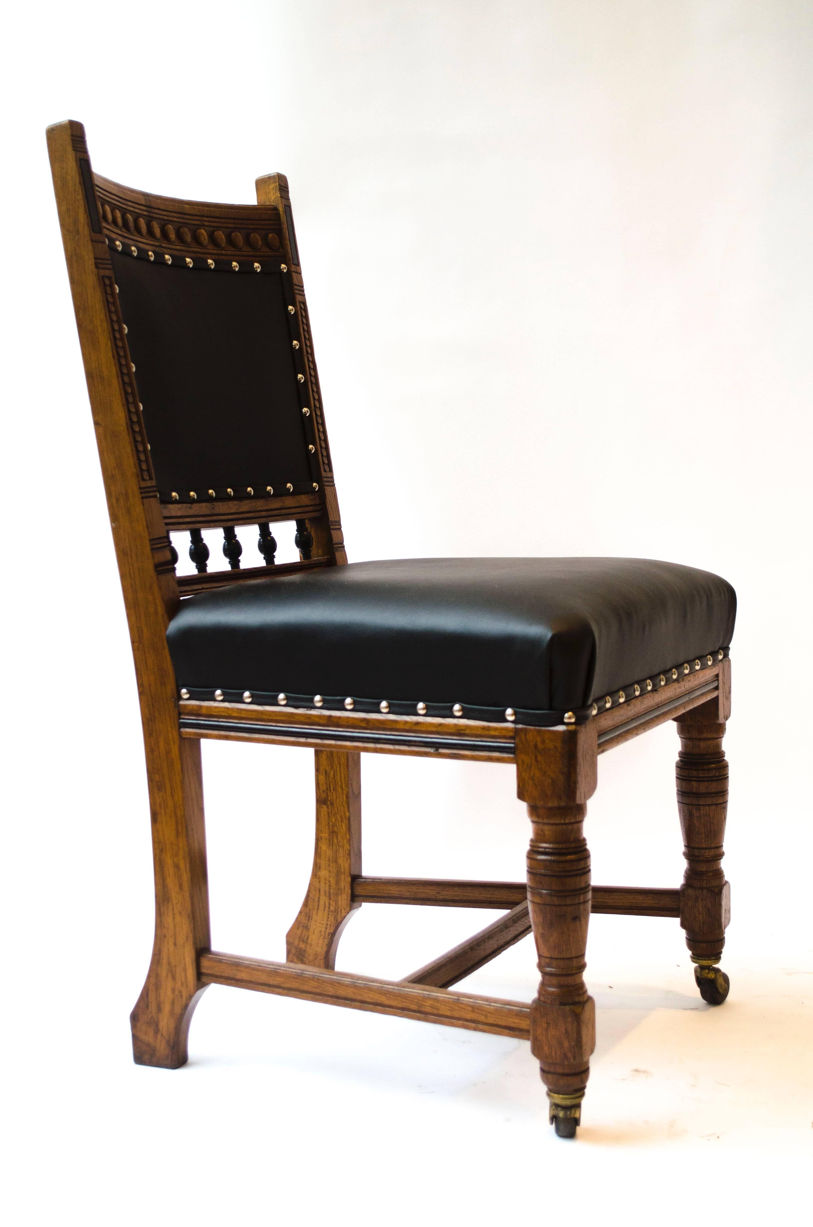 Lambs of Manchester A Set of Four Aesthetic Movement Oak Dining Chairs with carved and part ebonised details, professionally reupholstered in a quality matt black leather.