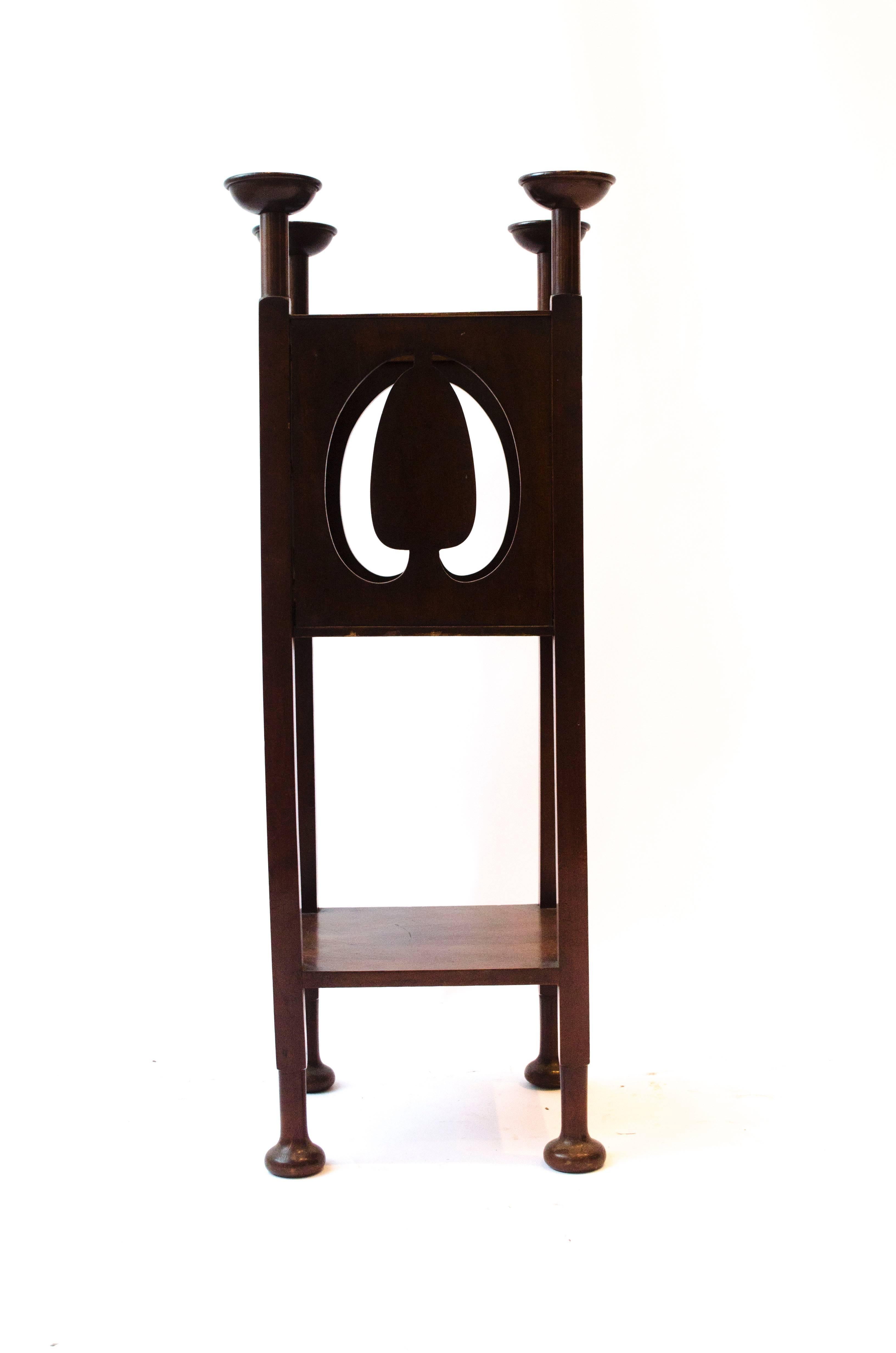William James Neatby (attributed).
An Arts and Crafts Glasgow Style mahogany plant stand, with elongated uprights, circular caps and stylized floral piercing to all four sides.