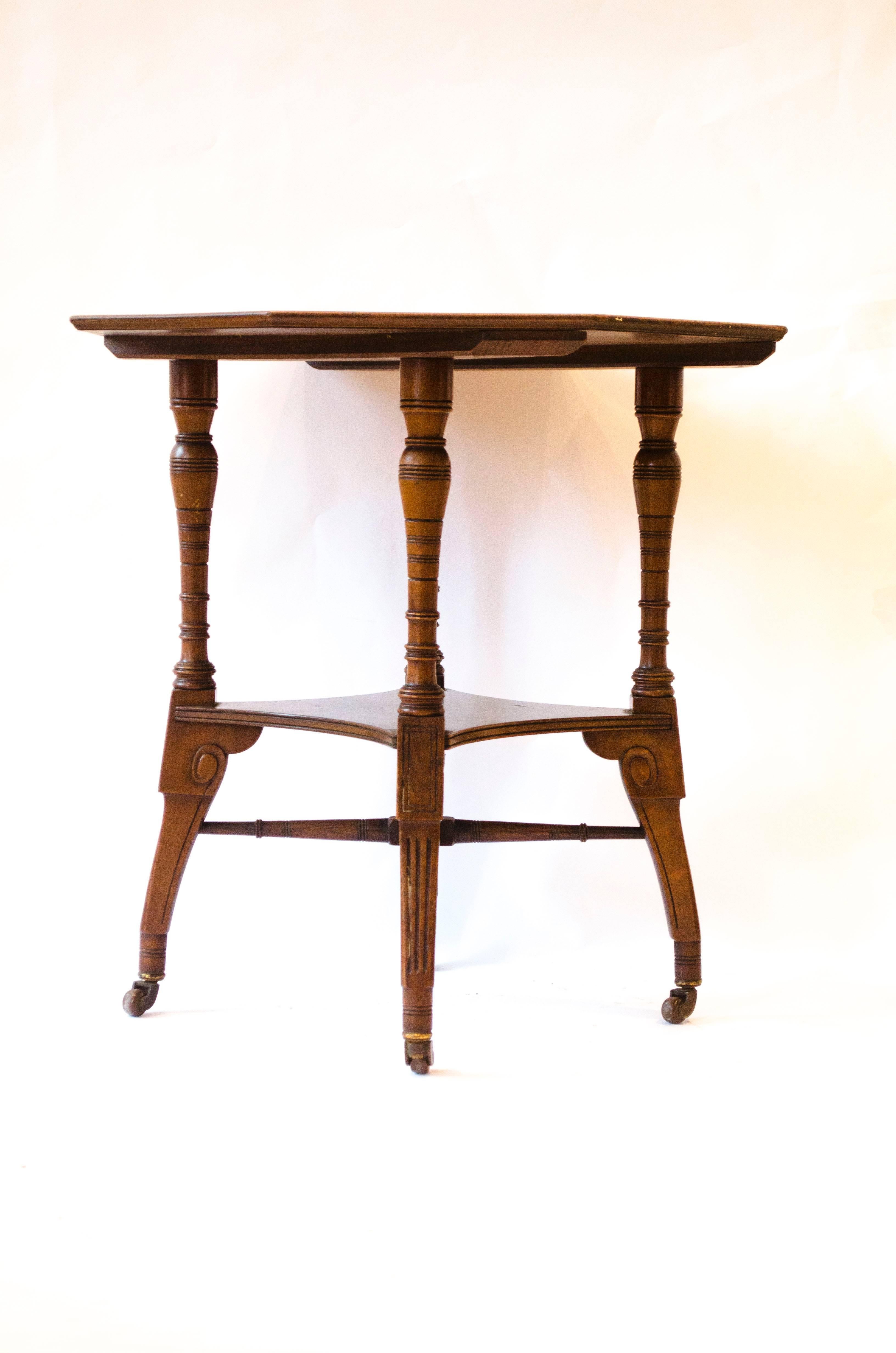 Jas Shoolbred.
An octagonal walnut center table with central shelf, carved circular details to the legs, united by lower cross stretchers.