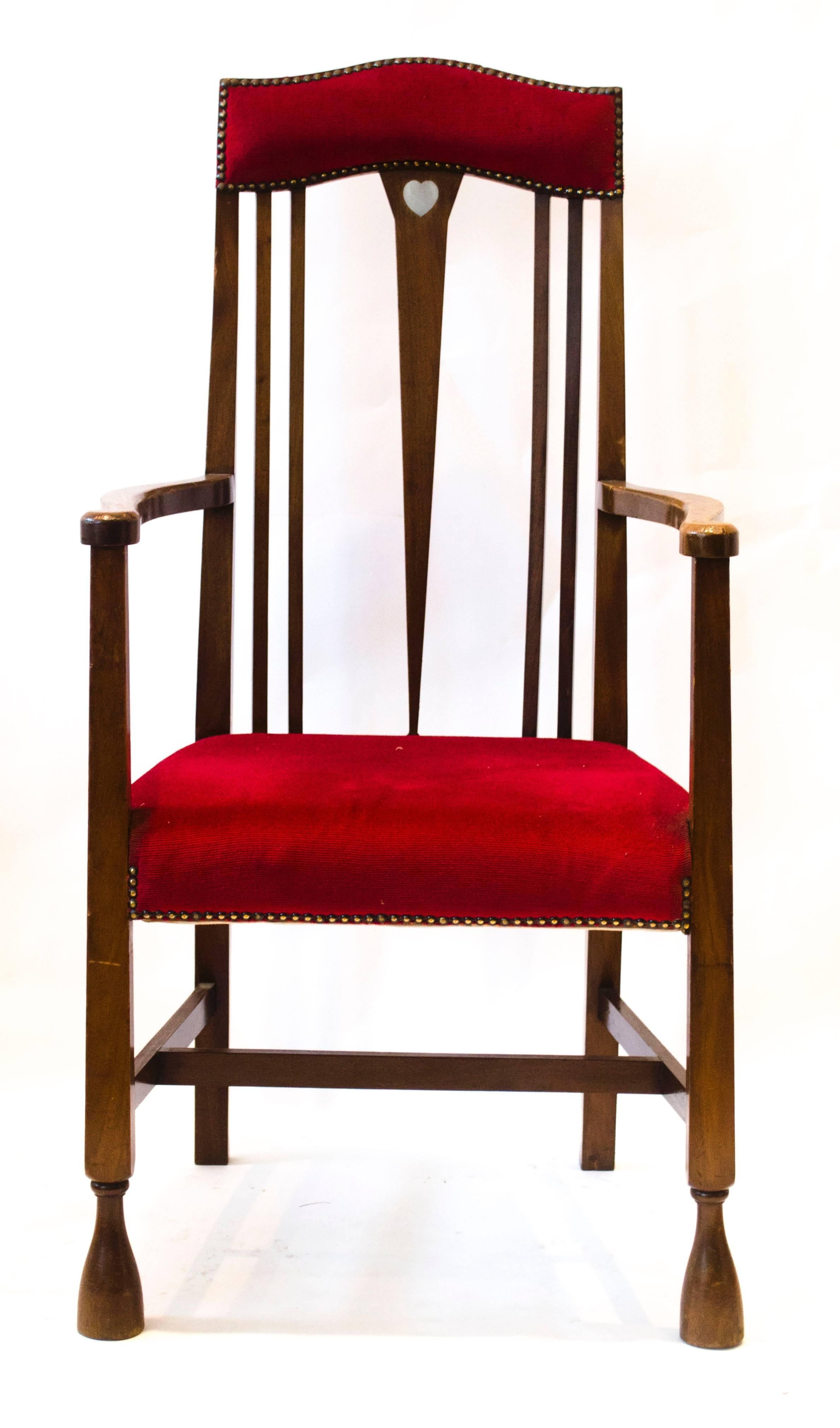 Liberty & Co, attributed. Probably made by Shapland & Petter.
An Arts and Crafts Mahogany armchair with shaped padded head rest inlaid with a single Voysey style pewter heart to the top of a fine tapering back splat with trumpet style feet.