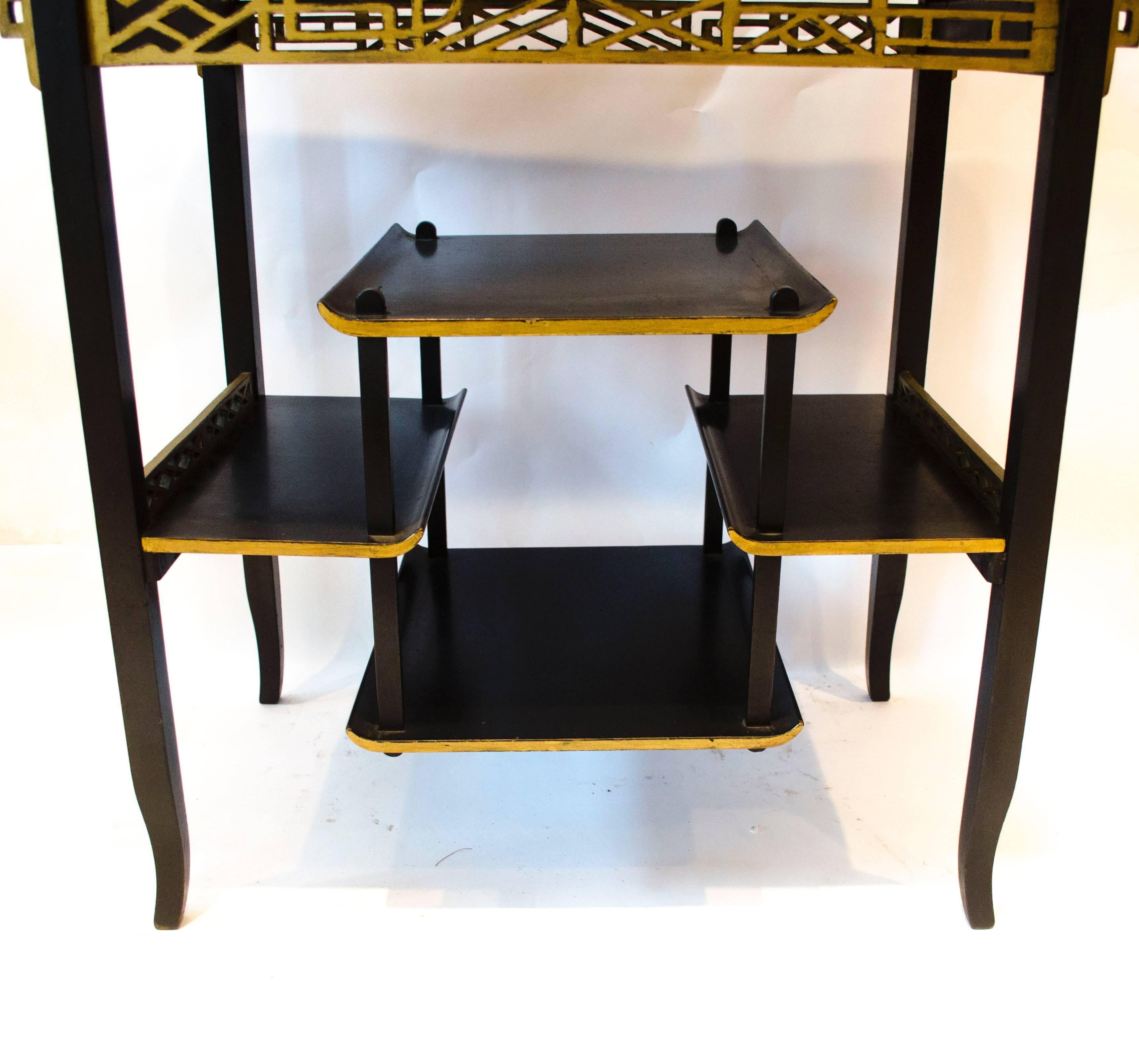 Heals. An Anglo-Japanese side table.
An Anglo-Japanese ebonised and gilt beech wood side table by Heals and Son, with flaring ends, gilt fretwork panels below and four shelves supported through each side in a stepped formation and further gilt