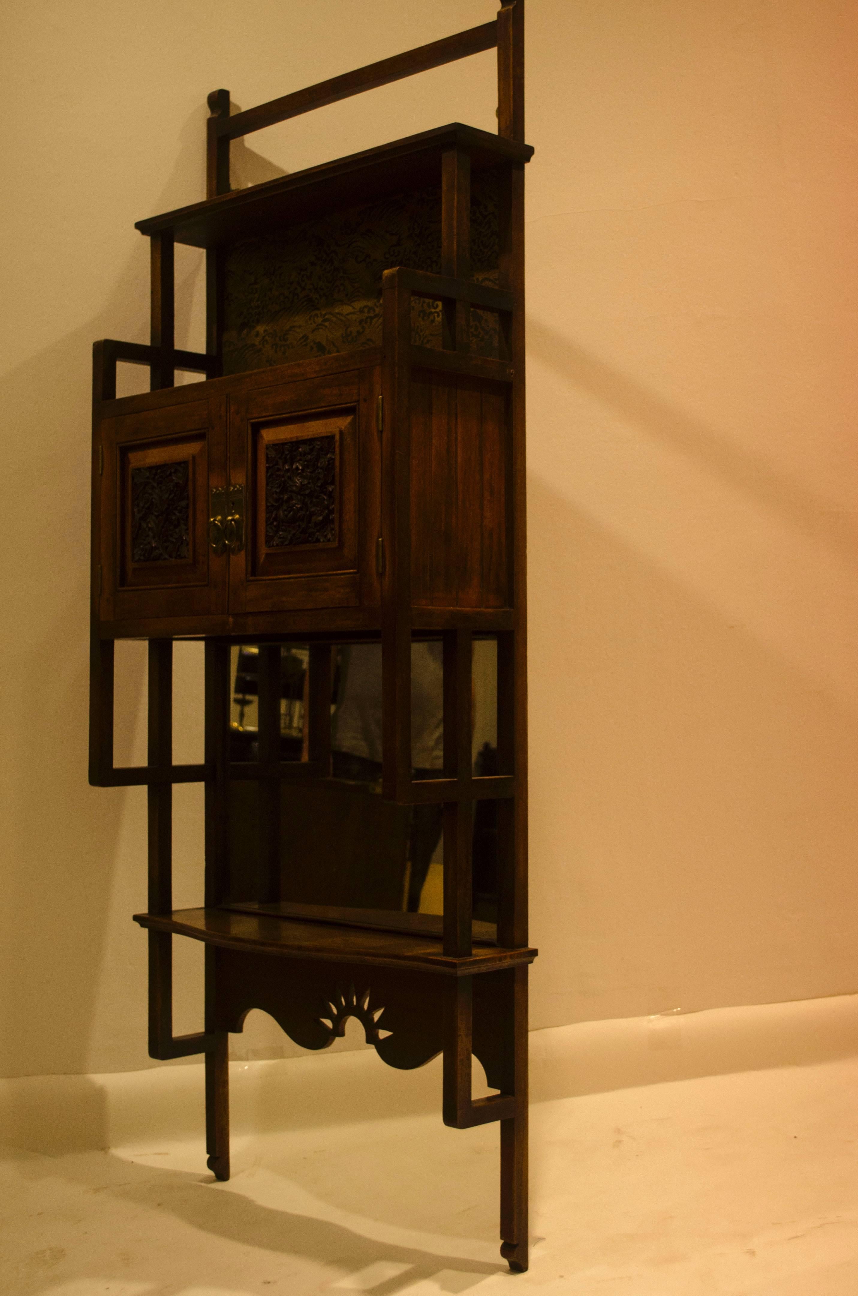 Made by The Bombay Art Furnishing Establishment
A rare set of Anglo-Japanese walnut wall shelves with ebonized and gilt-painted Japanese Carp to the upper panel, finely carved stylized floral details to the doors with a shaped shelf, and a mirror