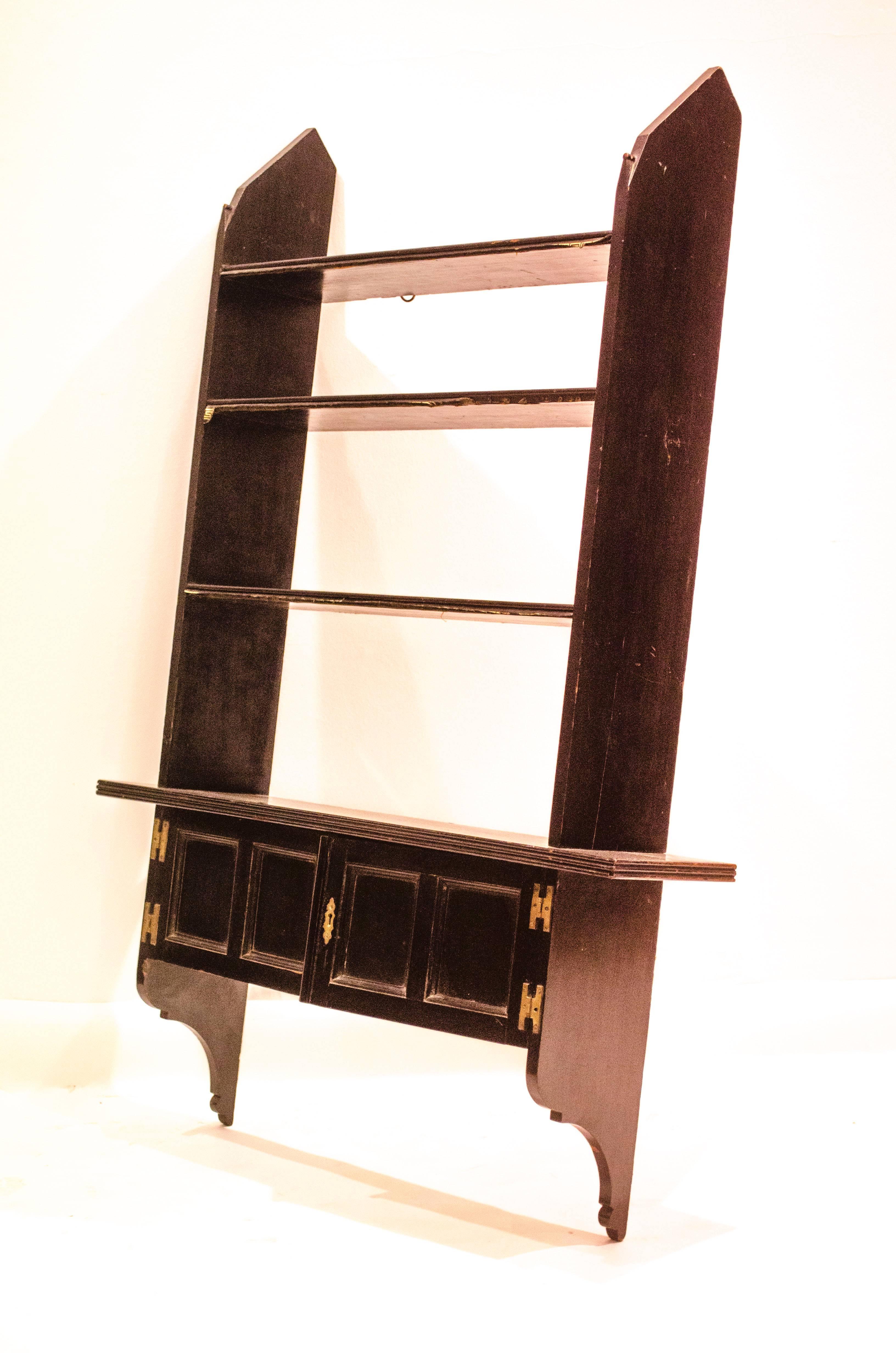 Edward William Godwin (1833-1886). Made by William Watt or Edwards and Roberts
A rare set of Anglo-Japanese ebonized hanging bookshelves with an extending lower shelf and a two-door hanging book cupboard beneath, brass hinges, and an