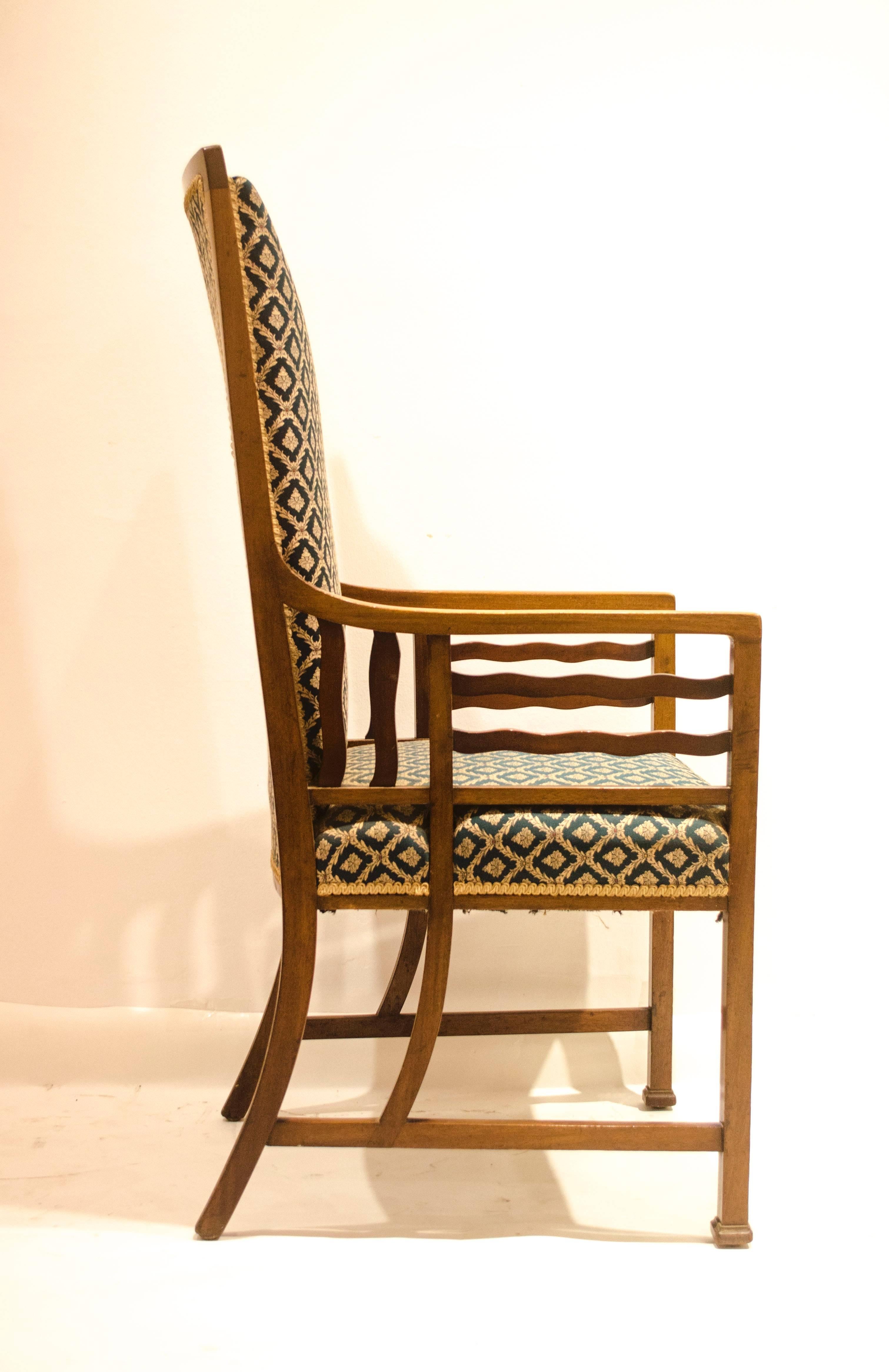 Liberty and Co. (attribué), un fauteuil anglo-japonais en noyer avec des supports d'accoudoirs ondulés et des accoudoirs qui se prolongent jusqu'aux brancards latéraux.