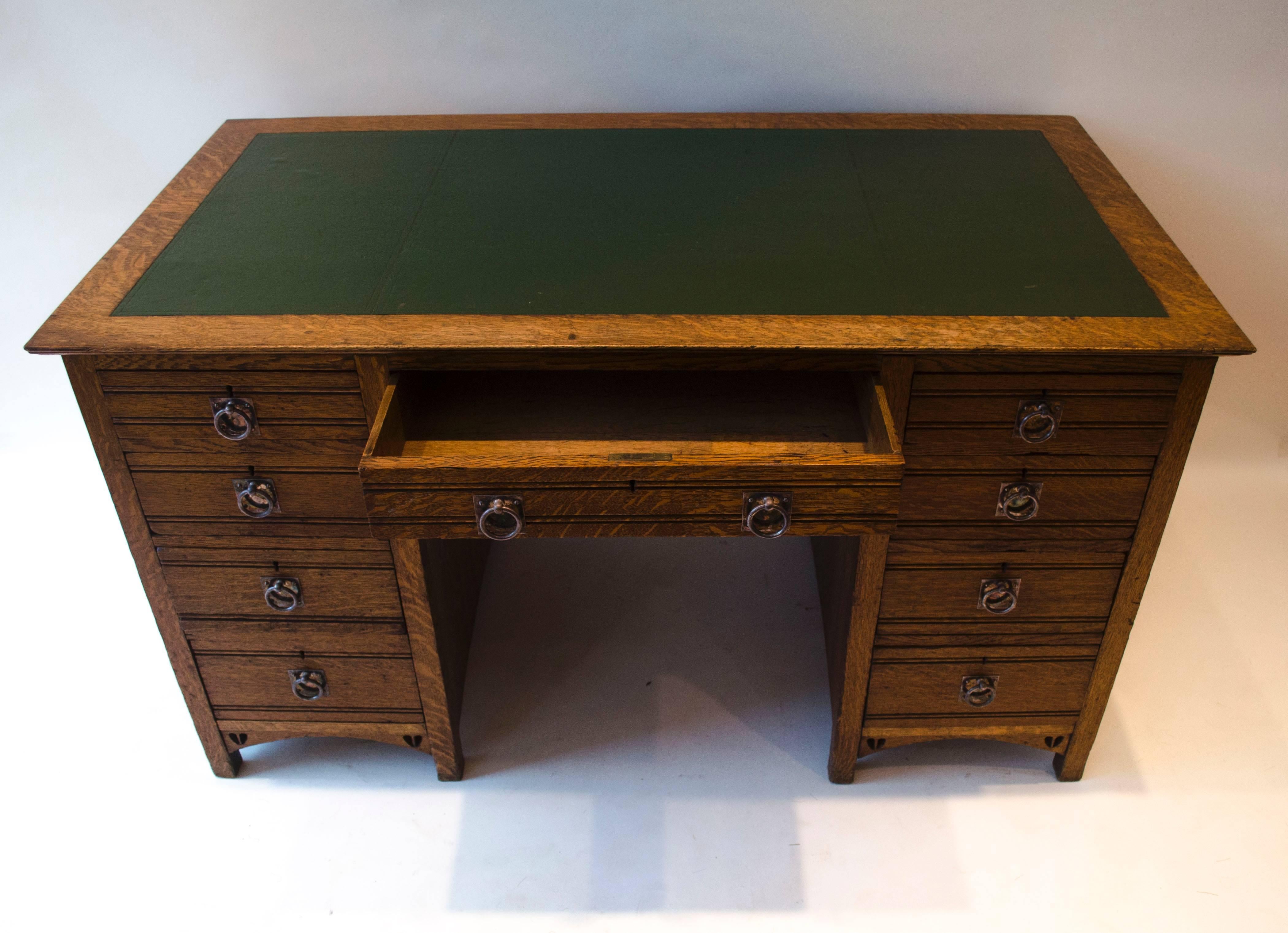 E. A. Taylor for Wylie and Lochhead. 
A pure Glasgow School oak twin pedestal desk with open writing area inset with green leather with tool-worked edges, a central upper drawer with sweeping curves pierced with Taylor's typical twin hearts to each
