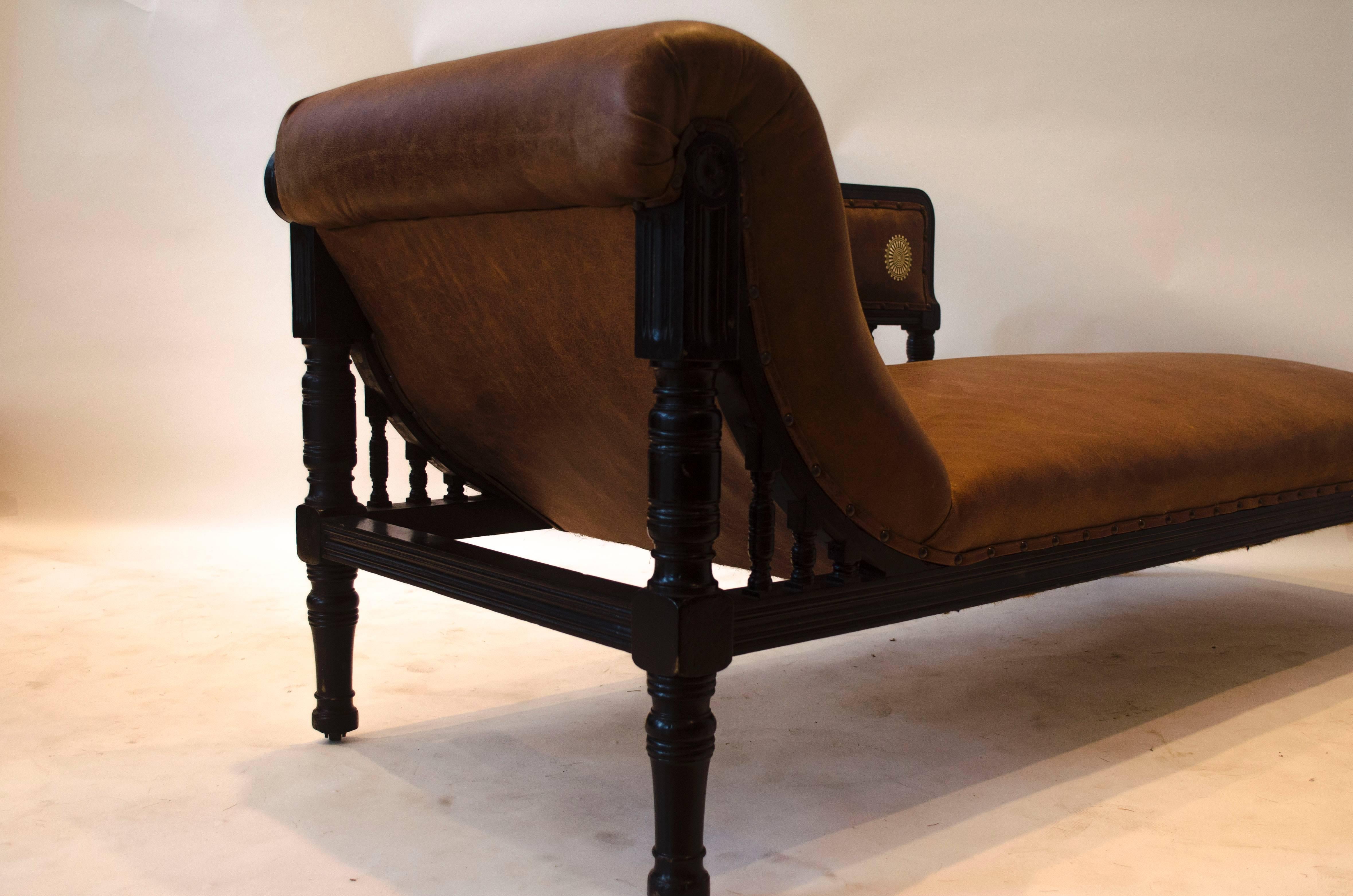 Edward William Godwin (attributed), an Anglo-Japanese ebonized chaise longue with later part gilt tooled leather upholstery, turned supports and spindles, with casters.
A design for a chaise longue is illustrated in William Watt's Art Furniture