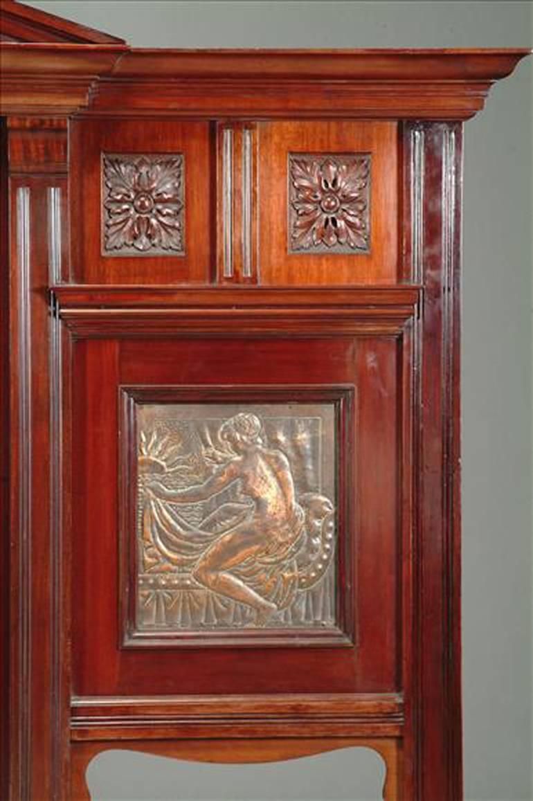 James Smithey, a superior quality Aesthetic Movement carved walnut over mantle, with bevelled mirror and embossed copper panels depicting classical maidens, one panel stamped 'JS 1894' (JS for Jame Smithey)