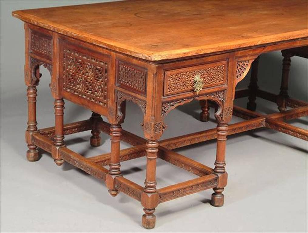 Liberty and Co (attributed), an Anglo-Moorish walnut partners' desk, with blind fret and full fret panels and drawers, flower carved niches, turned supports joined by stretchers, on block feet. The fretwork stylistically in keeping with the Moorish