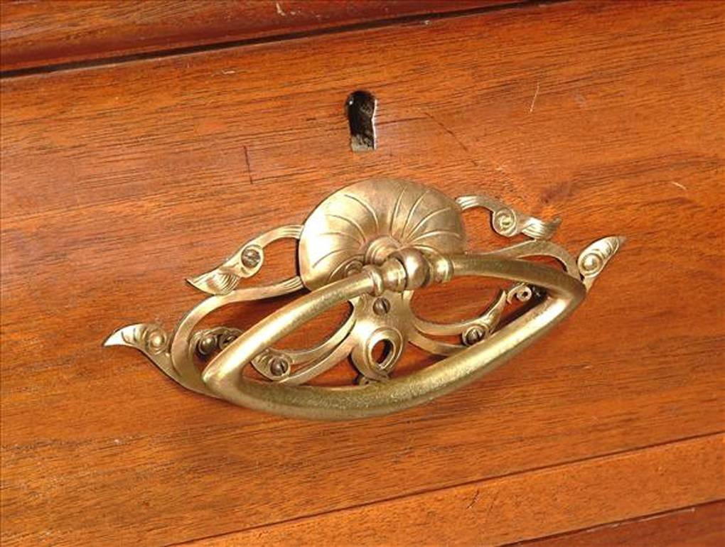 A French Art Nouveau walnut display cabinet, with foliate carving, an arch top, two bevelled glazed doors, eight drawers with Art Nouveau gilt brass handles, on foliate scroll feet. 
This is a good example of Nancy School work.
 