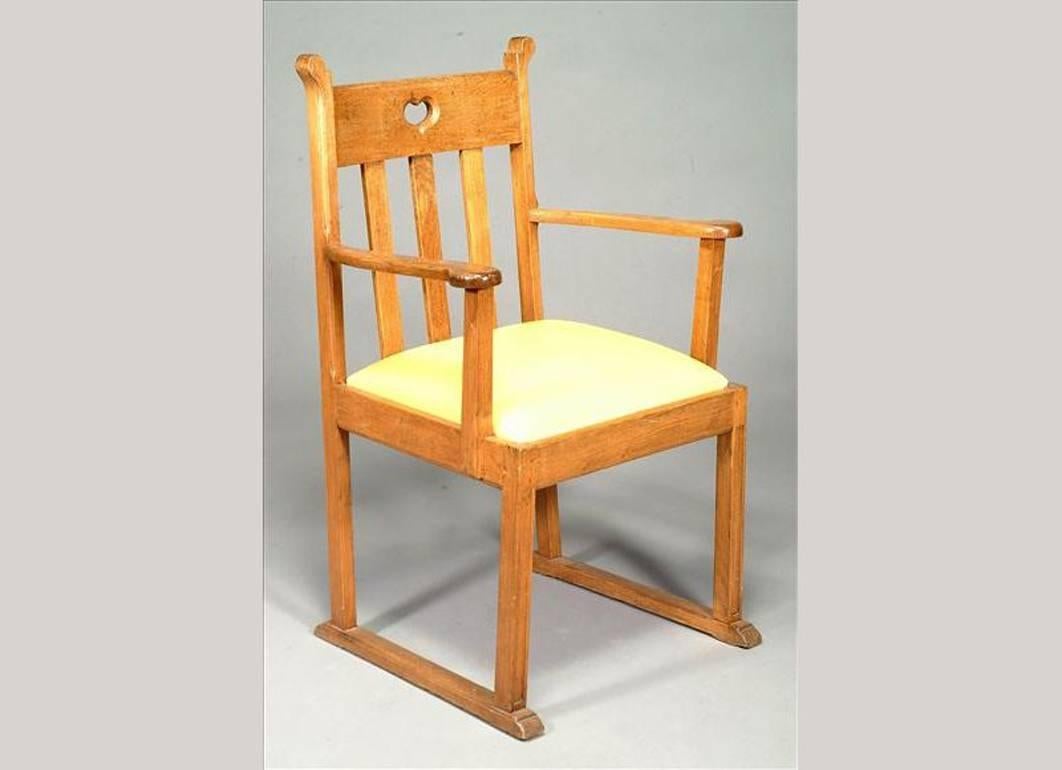 A pair of Arts and Crafts oak armchairs in the style of Liberty & Co, with heart cut-outs, and sledge style feet.