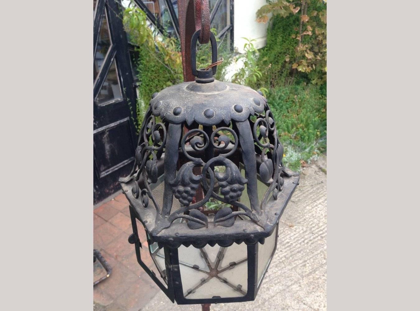 A good arts and crafts blacksmith made hammered iron lantern with beautiful scroll work details of entwined stylised petals and flower heads bursting with seeds.

