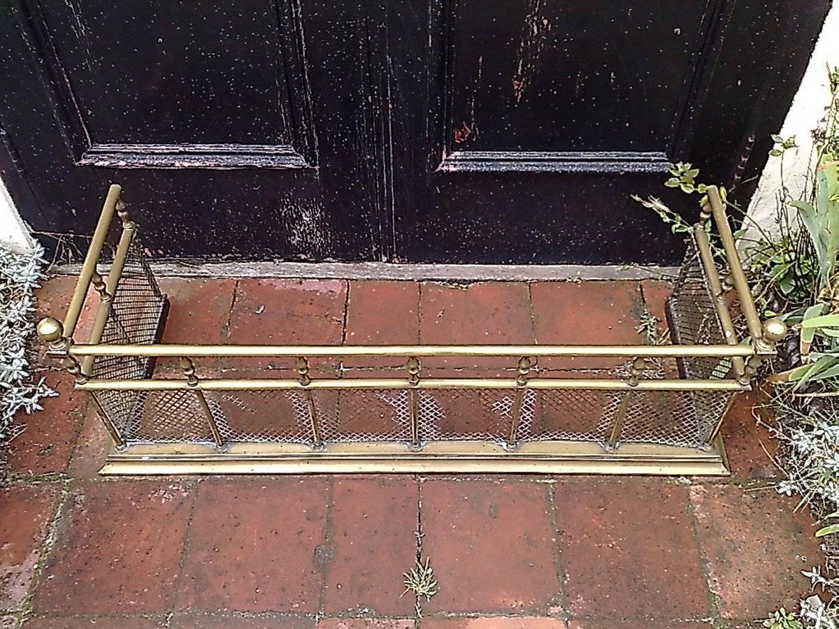 A good quality Aesthetic Movement brass fire fender with turned details and finials above, protective mesh to the lower part all stood on a solid brass plinth.