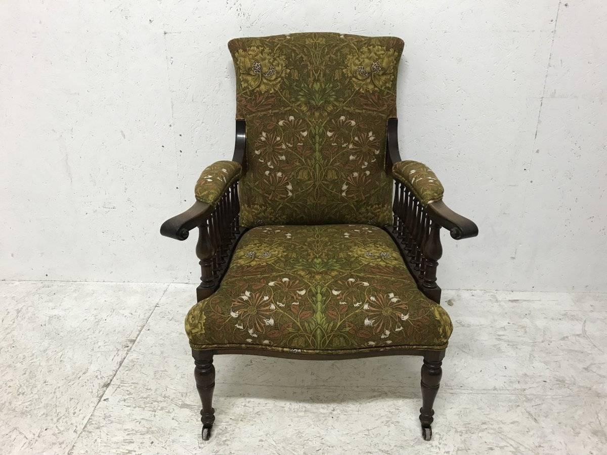 George Washington Jack for Morris and Co, a mahogany ‘Saville’ armchair, with wavy square arms spindles and on swollen front legs with later conforming casters. Professionally re upholstered in a high grade Morris and Co upholstery fabric by