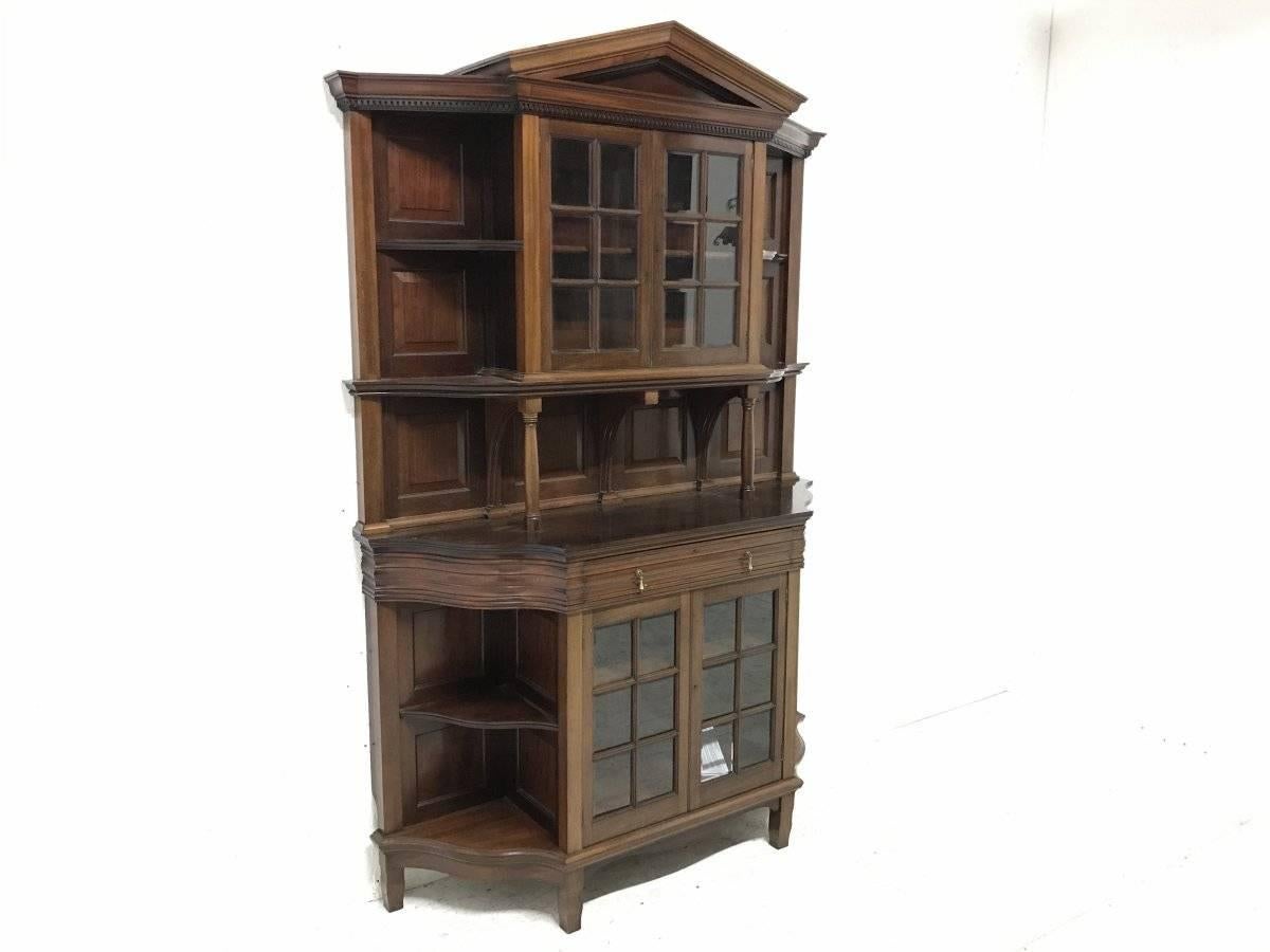 Morris & Co. A fine mahogany glazed breakfront bookcase designed by George Jack of exceptional quality typical to all Morris & Co furniture. With upper and lower central glazed sections both flanked by open semi-serpentine corner shelves with a
