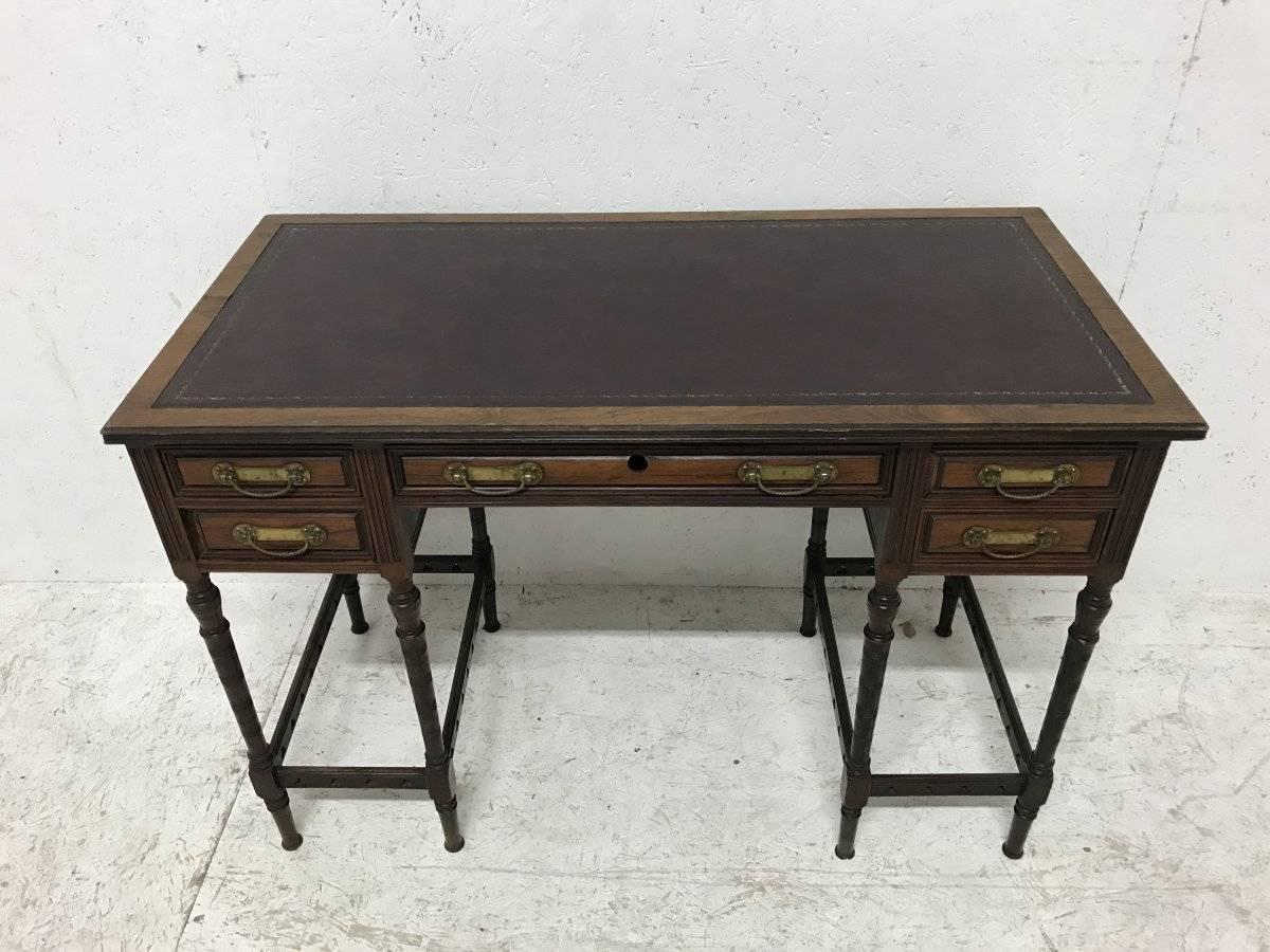 Collinson and Lock. Attributed to E W Godwin. An exceptional quality rosewood writing table with five upper drawers and stylized swan neck drop handles with eight finely turned legs each set of four united by circular pierced details. 
Renewed