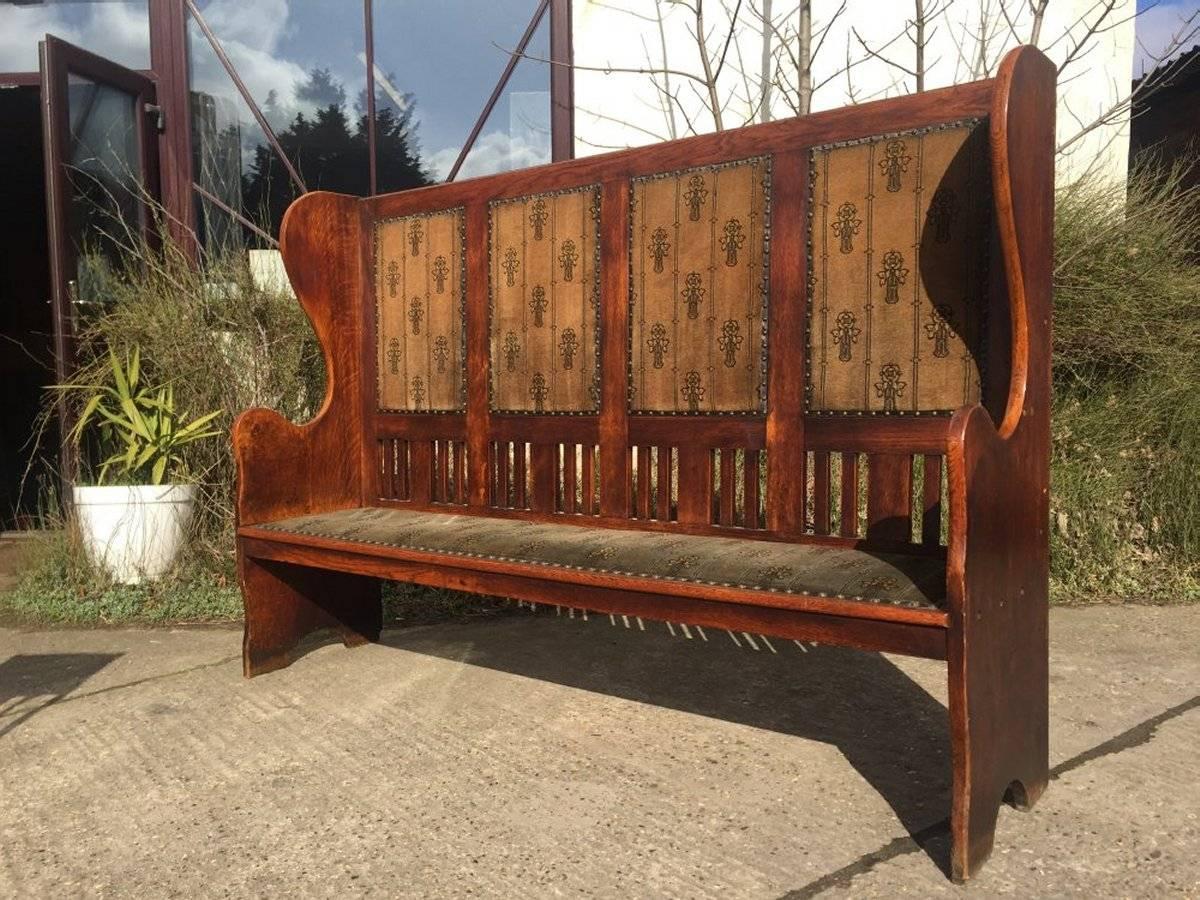 An Arts and Crafts Glasgow School oak settle in the style of M H Baillie Scott. Made by Wylie and Lochhead with sweeping curvaceous ends and a lower slatted detail, retaining it’s original fabric with fantastic stylized Glasgow Roses which I must