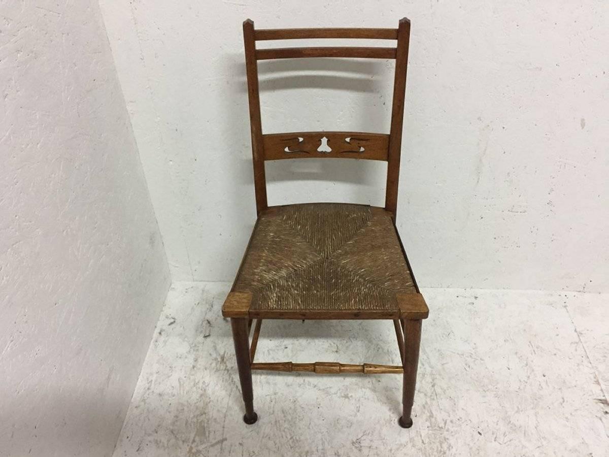 An Arts and Crafts rush seated side or bedroom chair probably made by Wylie and Lochhead with stylized tulip cut-outs to the back retaining it's original rush seat in great condition.