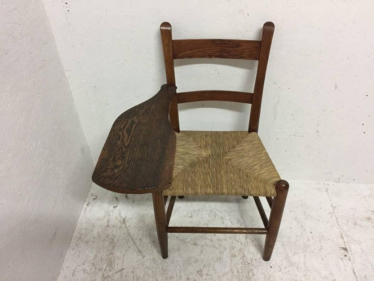 William Birch. An Arts and Crafts oak artist's sketching armchair with a shaped top for sketching or writing on. The shaped top supported on the upper leg with simple decorative hand-wrought iron work.
Measure: The width is 23