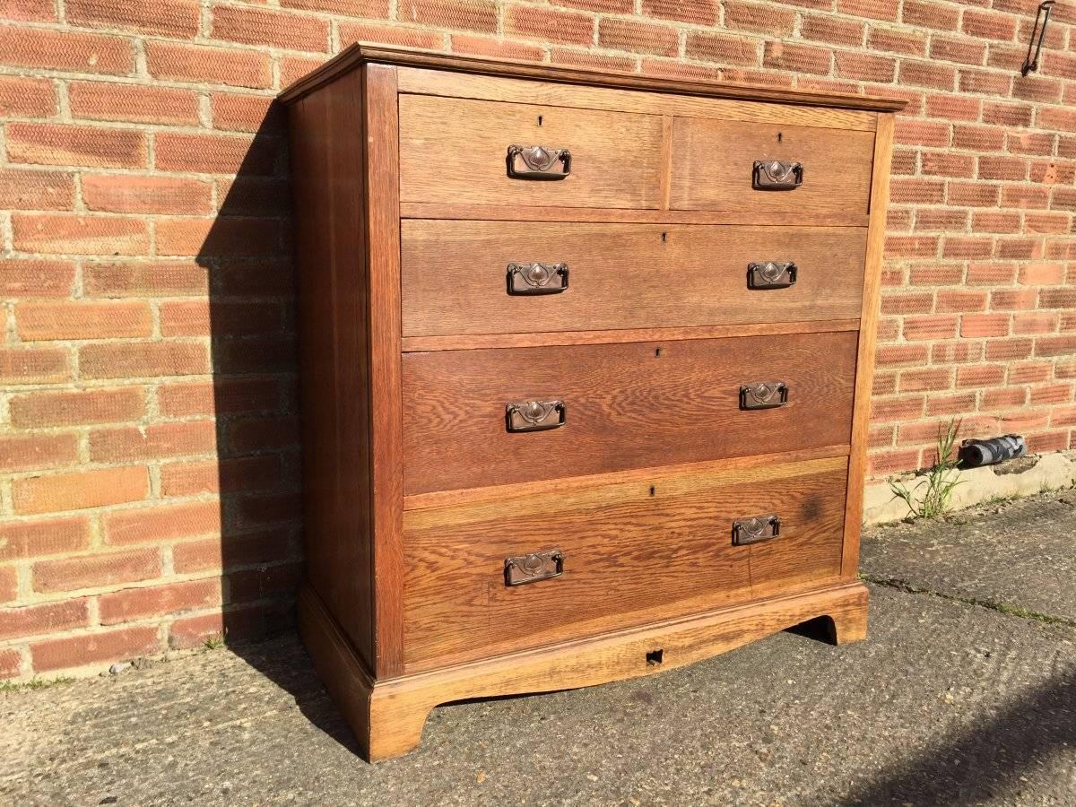 Liberty & Co attributed. A good Arts & Crafts oak chest of drawers with copper floral handles and a single pierced tulip to the centre of the sweeping skirt at the base, on ogee feet.