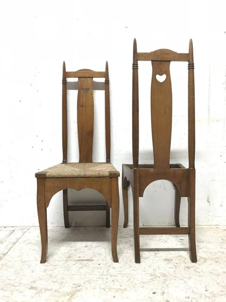Shapland & Petter. A pair of Arts & Crafts oak dining or side chairs in the style of George Walton with finely turned tops, pierced hearts to the backs with lower arched aprons and Queen Anne style legs. 
Although only one is shown both rush seats
