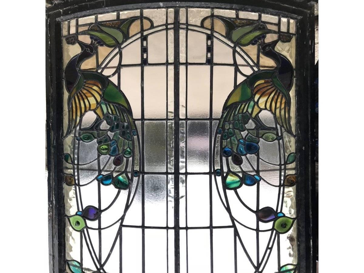 A rare and exceptional Arts and Crafts stained glass bow fronted window with colourful peacocks to each side. The coloured glass details to the tail feathers are so very life like and and in similar shapes of small pebbles giving a deep three