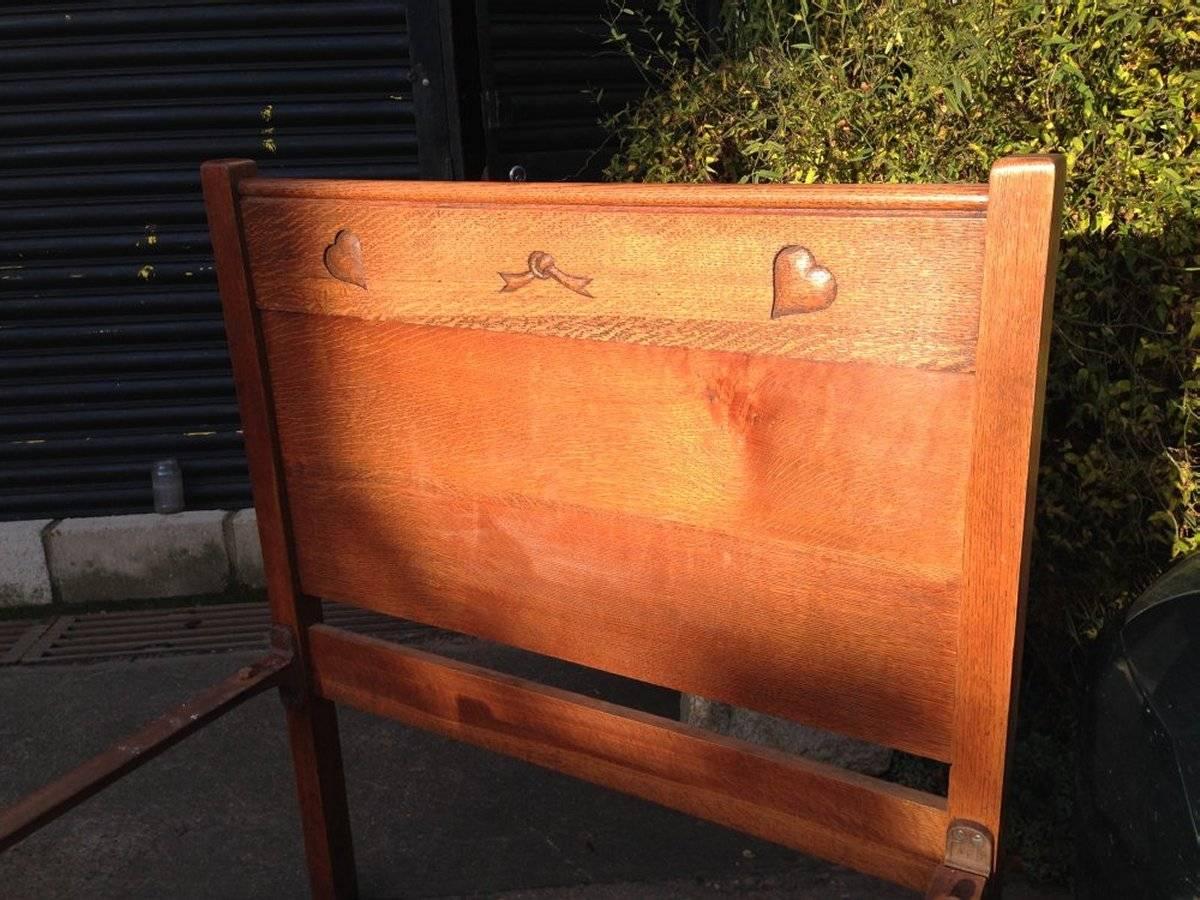 Heals and Son. A near pair of Arts & Crafts 3 foot wide single oak beds with carved heart details, one also with a carved tied knot.
 