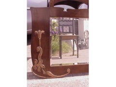 An Arts & Crafts Shaped Oak Bevelled Mirror with Stylised Floral Copper Details