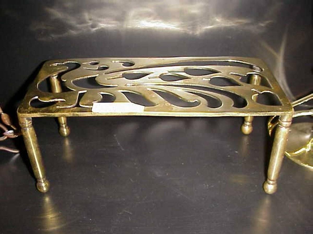 An Aesthetic movement brass trivet with peacock fret work, on turned legs.