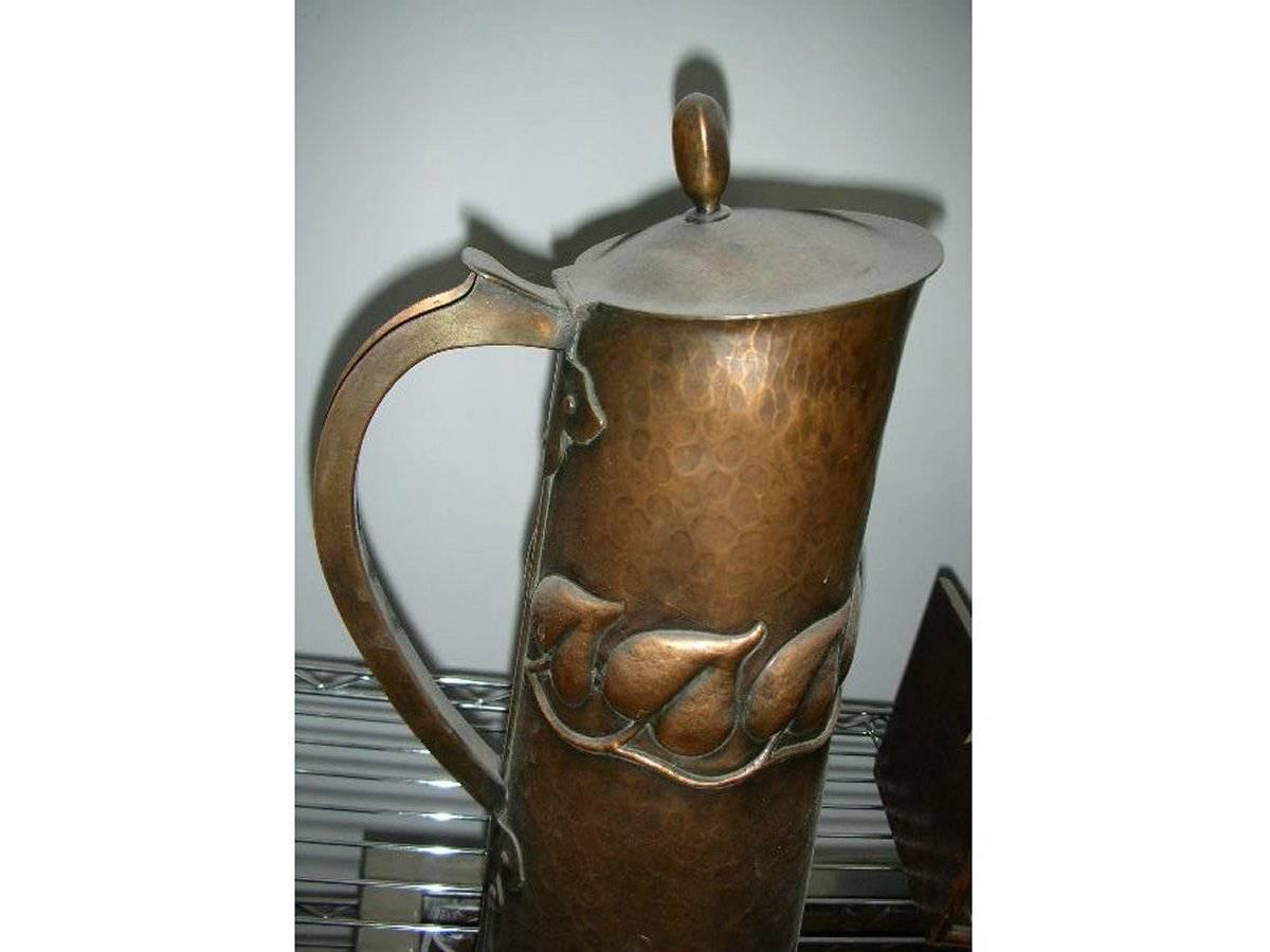 An Arts & Crafts copper jug with stylised repousse leaf details and Acorn finial. A high quality handmade jug. Unmarked.