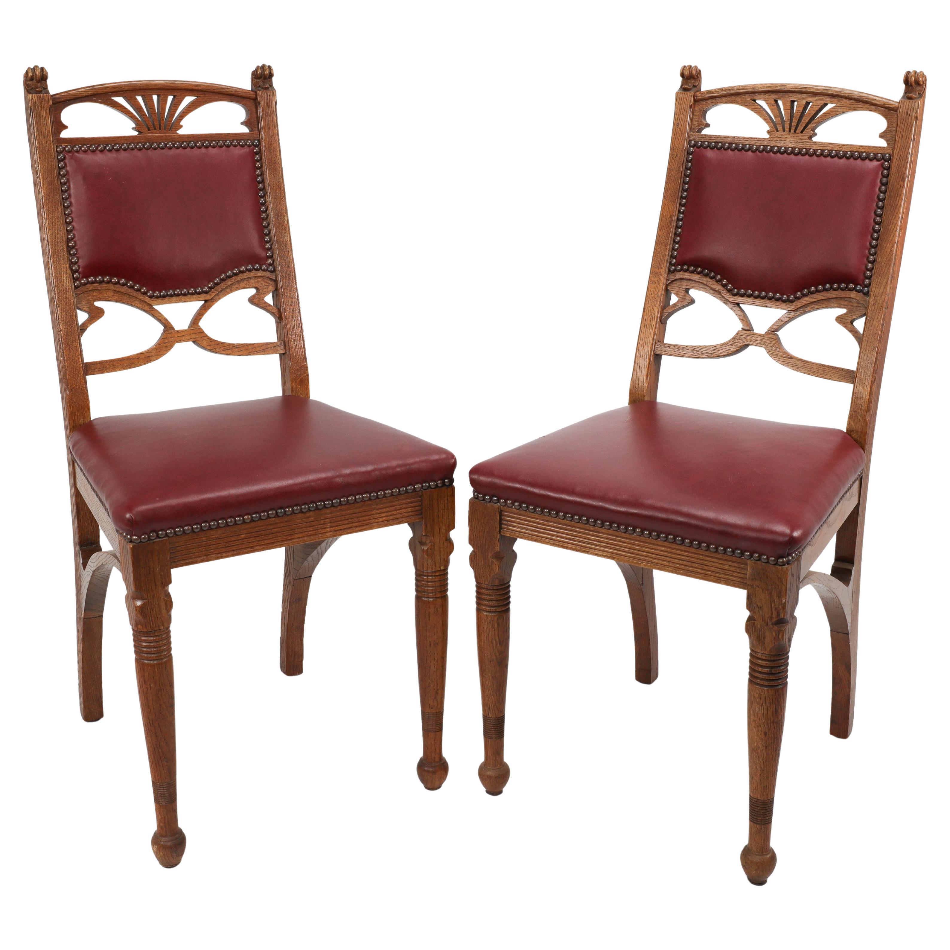 A pair of French Art Nouveau oak dining chairs with whiplash side stretchers