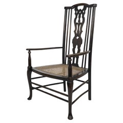 Liberty & Co attribué. Fauteuil de style Queen Anne à dossier chantourné et assise en rotin.