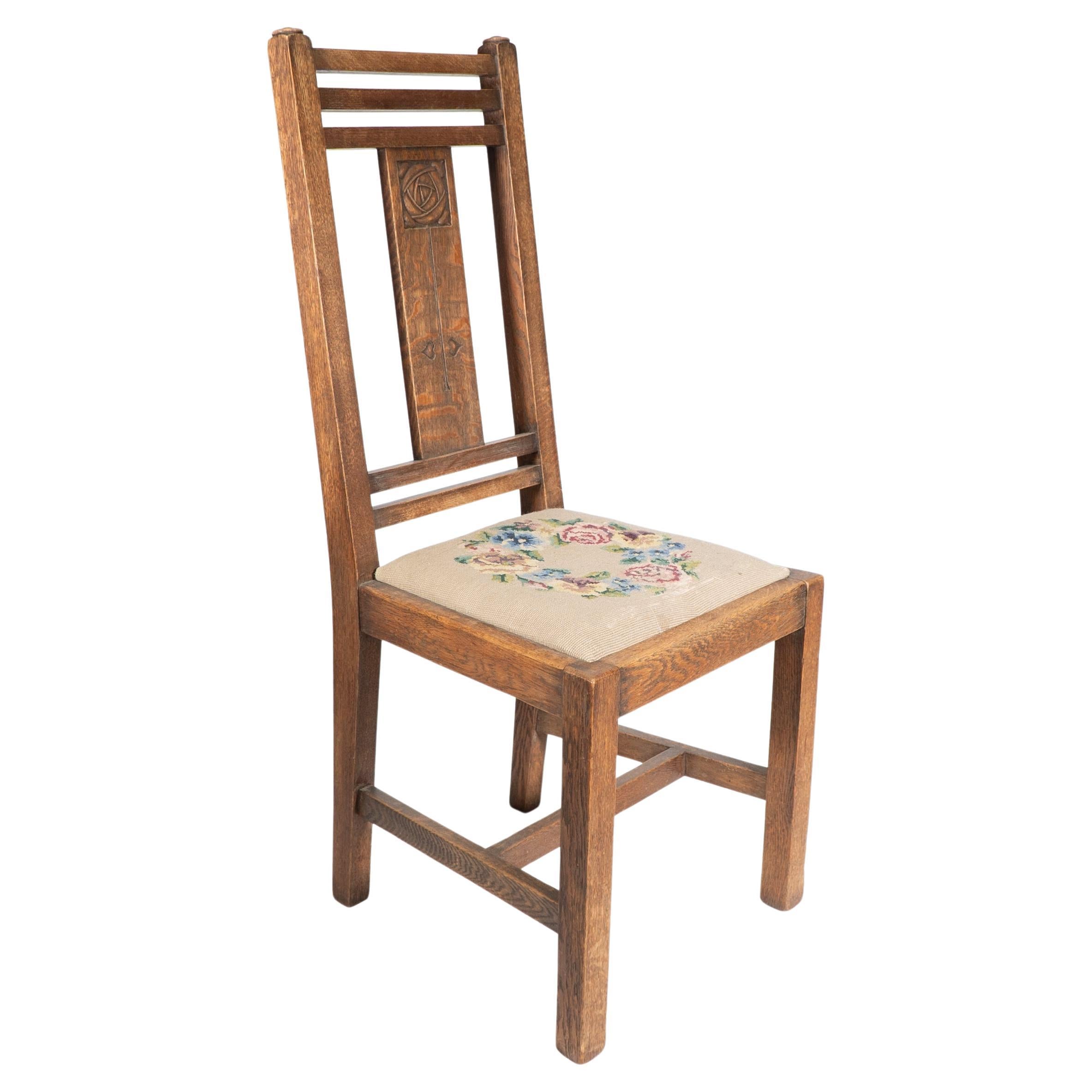 Liberty & Co. An Arts & Crafts oak chair with carved rose decoration to the back For Sale
