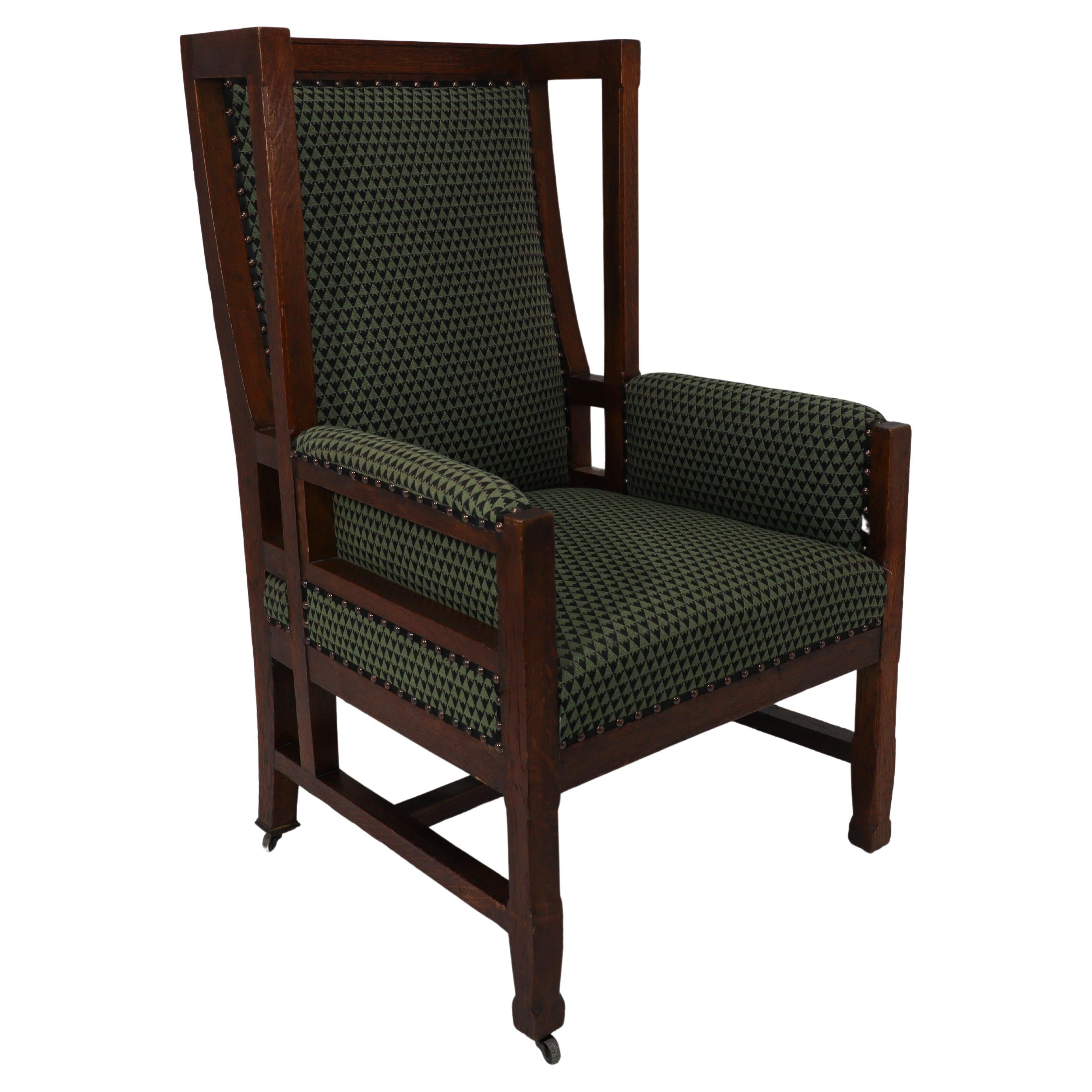 Liberty and Co, attr. in the style of Leonard Wyburd. An oak wing back armchair For Sale