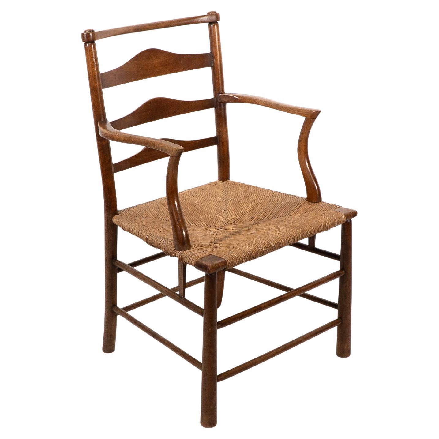 C R Ashbee. An Arts and Crafts rush seat ladder back armchair For Sale