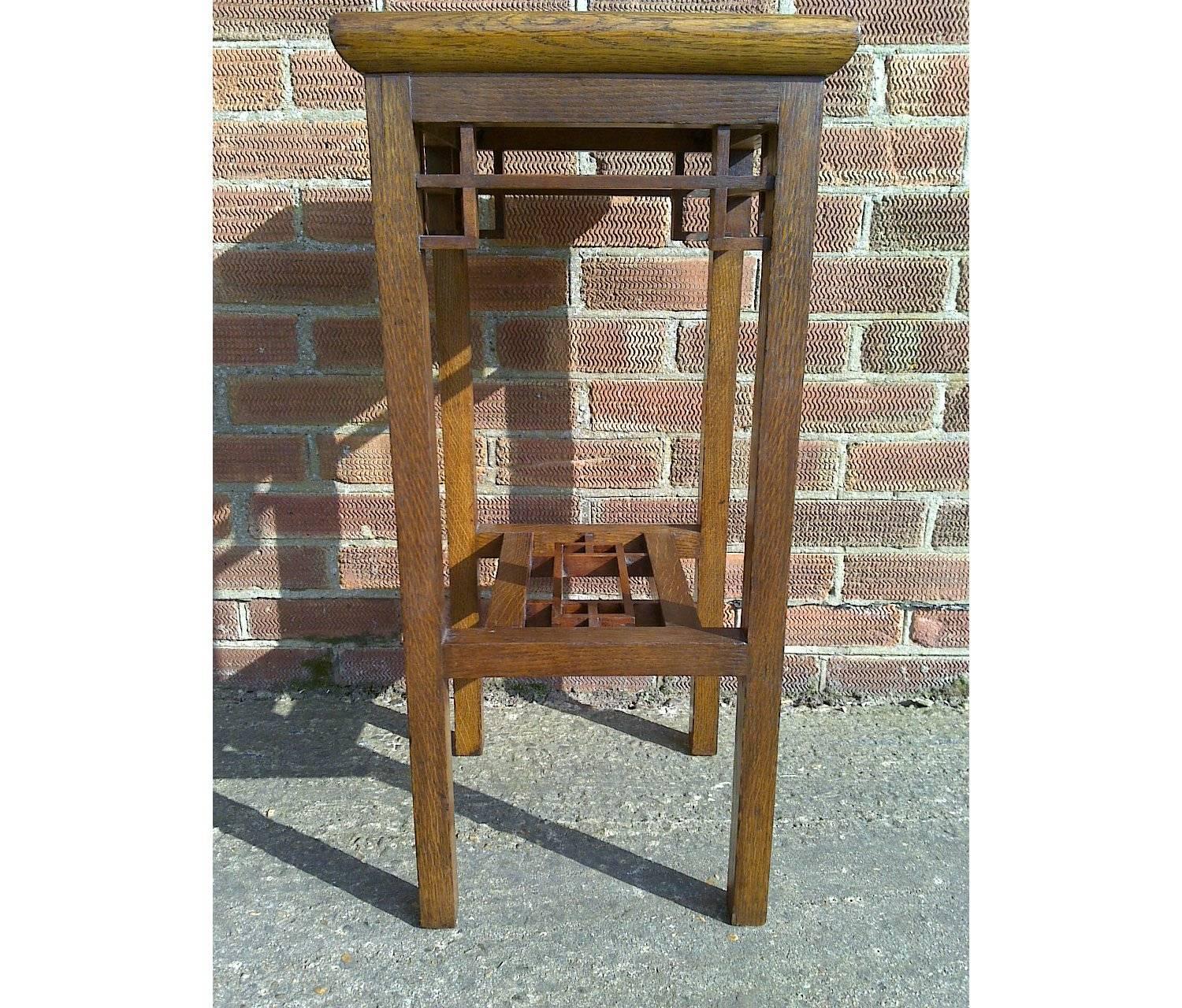 E. W. Godwin William Watt,. Probably made by William Watt.
An Anglo-Japanese oak statue or plant stand with wide inlaid top, tiny dovetail joints to the lattice work supports on square legs united by a lattice under tier. 