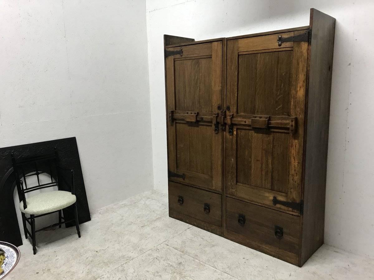 Wylie and Lochhead. A rare Arts and Crafts large oak wardrobe with stylised iron hinges and latch style handles to the doors which open to reveal twin hanging space, with two deep drawers below.
 