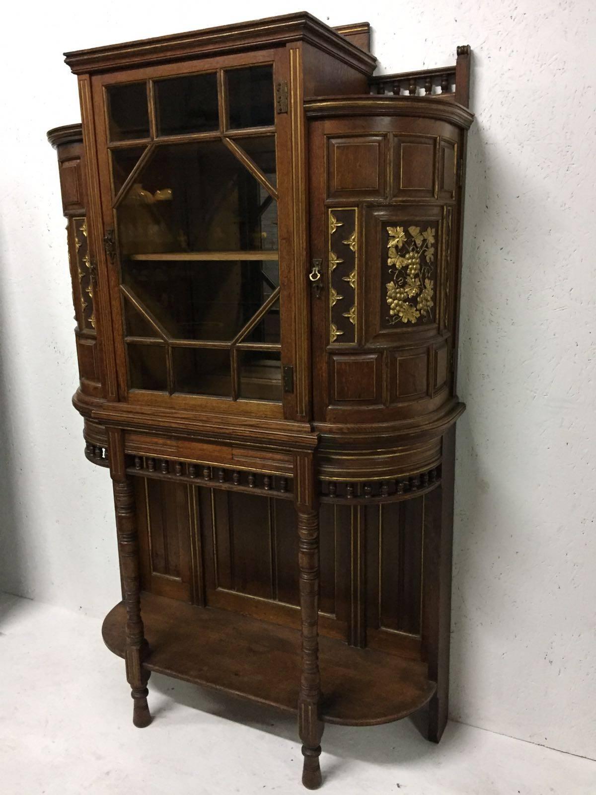 Bruce Talbert attributed to Gillows. 
A rare Aesthetic Movement oak cabinet with parcel-gilt carving to the demilune doors depicting vine grapes and a butterfly to the right, and the passion of Pomegranates carved to the left.

A similar corner