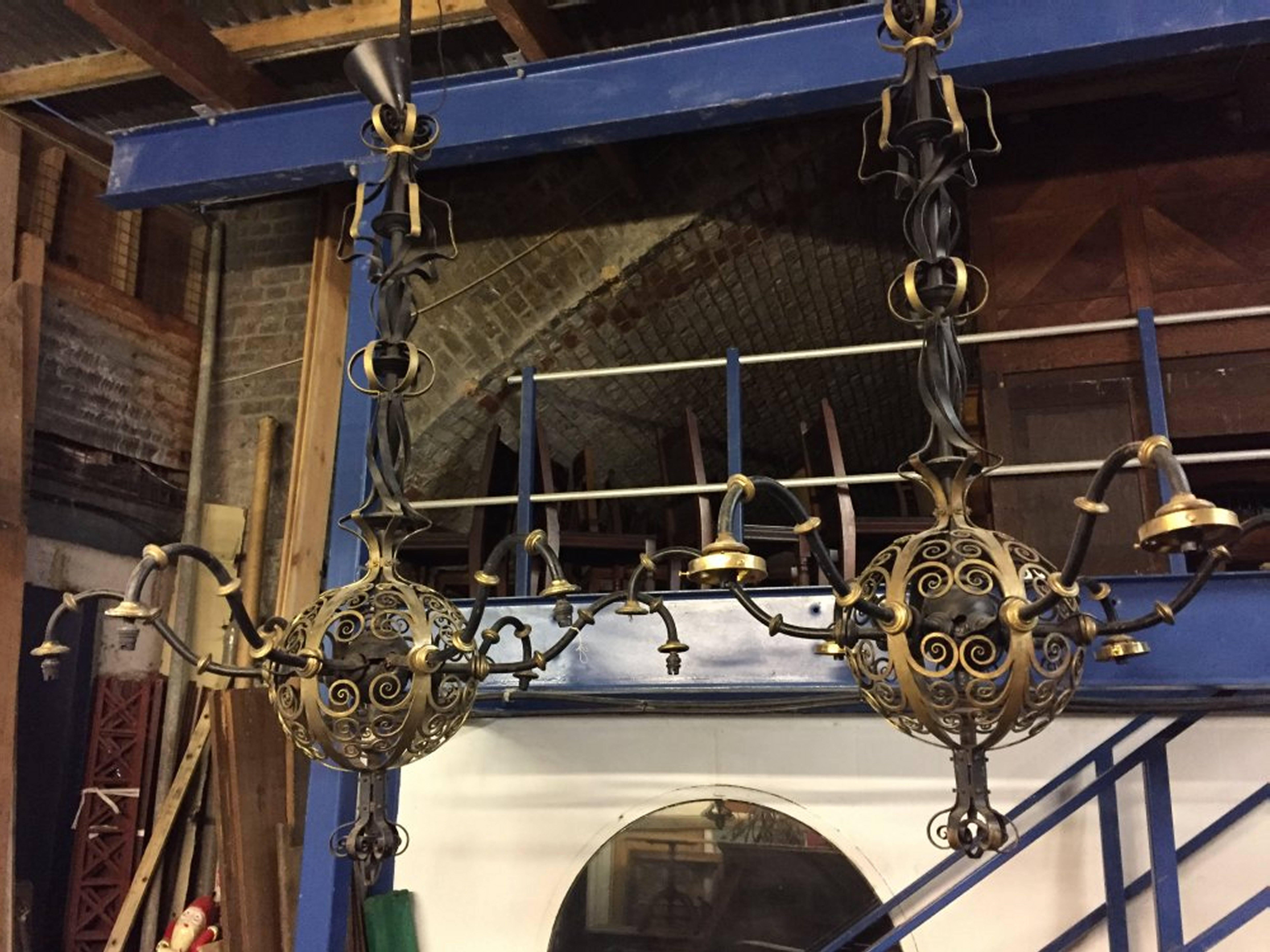 Spital and Clark of Birmingham. Attributed. A set of three ‘enormous’ Arts and Crafts blacksmith made six-arm chandeliers. A charming interlacing stem within writhen central form, with spherical centre piece decorated with scrolling details that