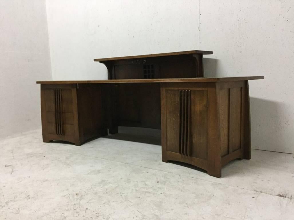 A custom-made oak desk in the style of Charles Rennie Mackintosh. This desk was hand made from solid oak in the late 1980s. It was designed by an architect  for an architect's office. It has a large storage cupboard to the right and a bank of four