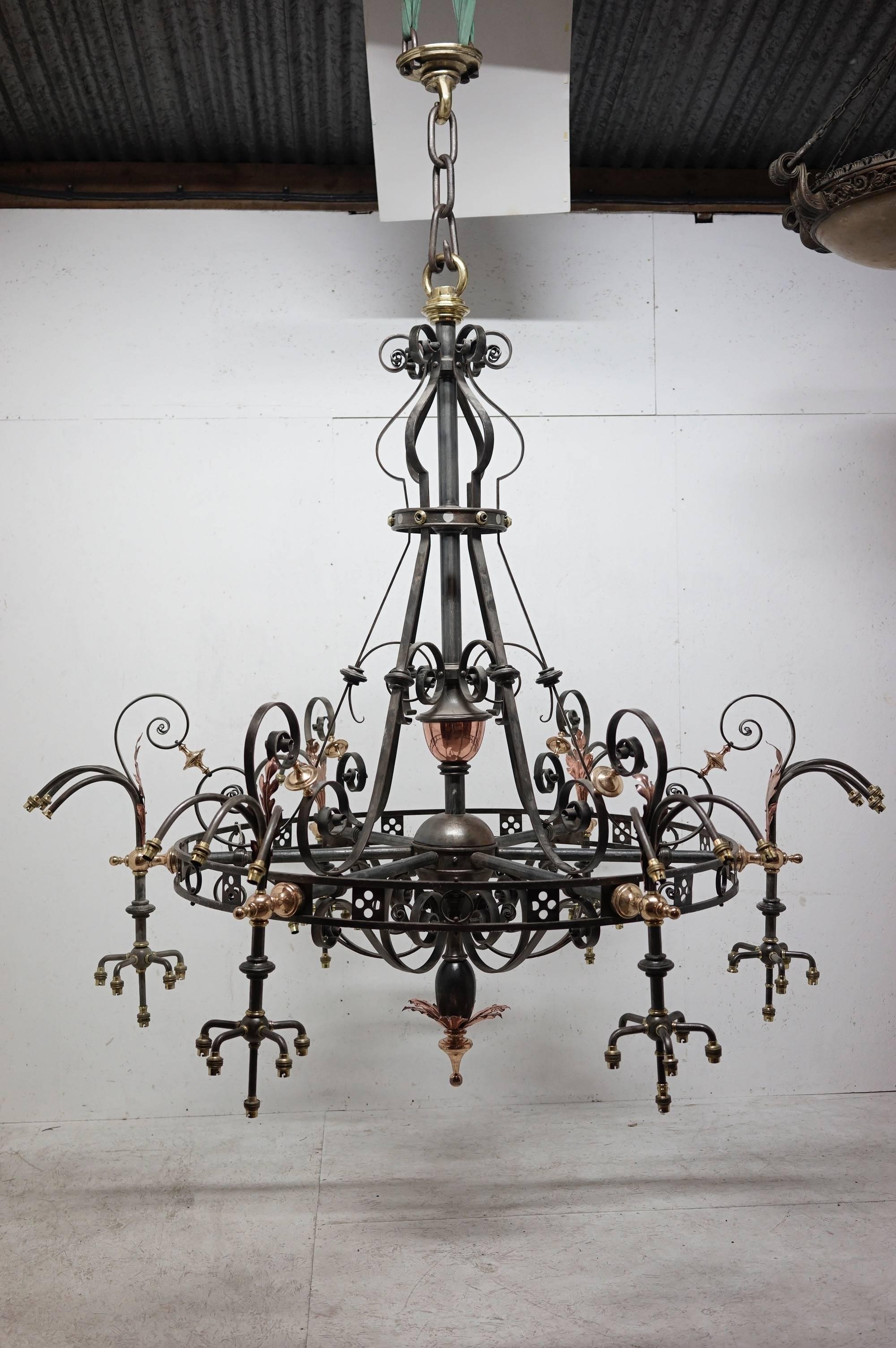 An outstanding enormous Arts & Crafts brass and iron chandelier with a subtle Gothic Revival influence originally from St Georges Church in Glasgow. Measure: 9' high x 7' 4