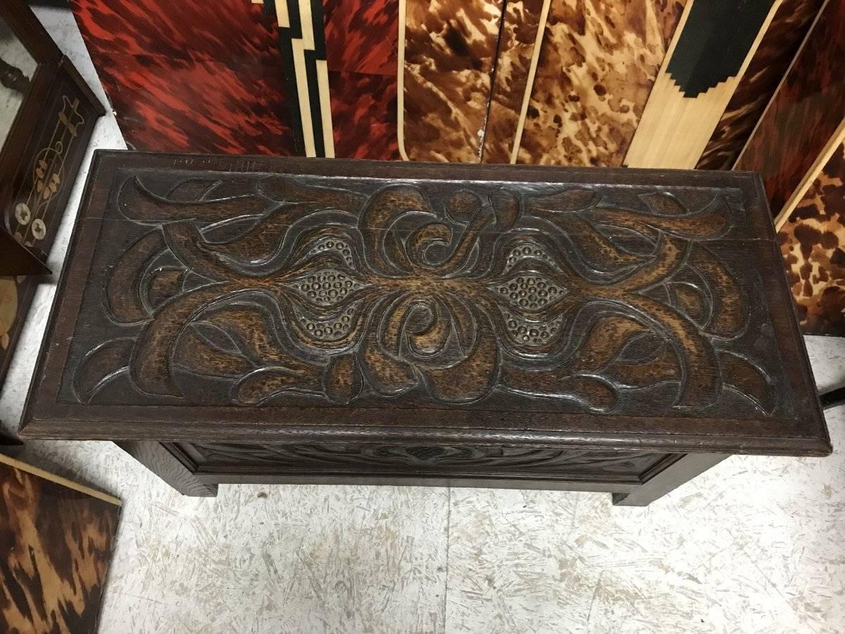 A rare Arts & Crafts oak linen trunk attributed to C R Ashbee and probably made by the Guild Of Handicraft, with well-executed carved stylized poppy seeds and interlacing leaf details.