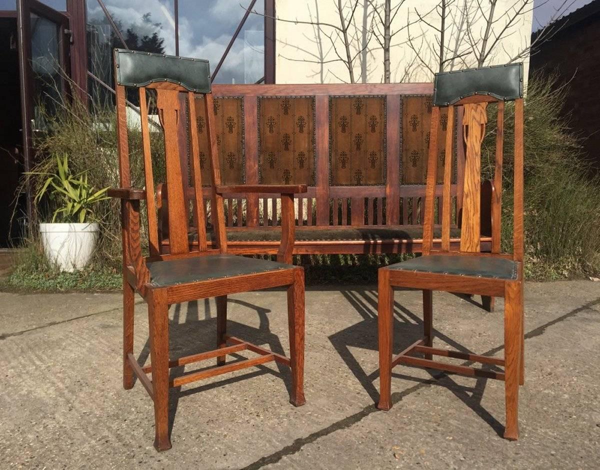 E A Taylor attributed, probably made by Wylie & Lochhead.
A set of twelve Arts & Crafts Glasgow school tall back oak dining chairs with leather head rest and subtle tulip detail to the back and twin central stretchers uniting the side