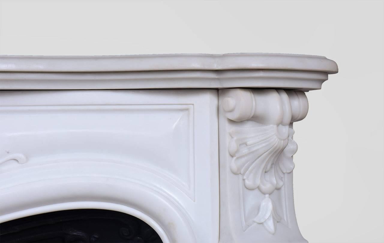 “Madame Du Barry” is a Louis XV style marble fireplace in white Carrara marble.

The generously curved shape is elaborately decorated with finely carved plant motifs. The center of the entablature of this custom fireplace is decorated with a large