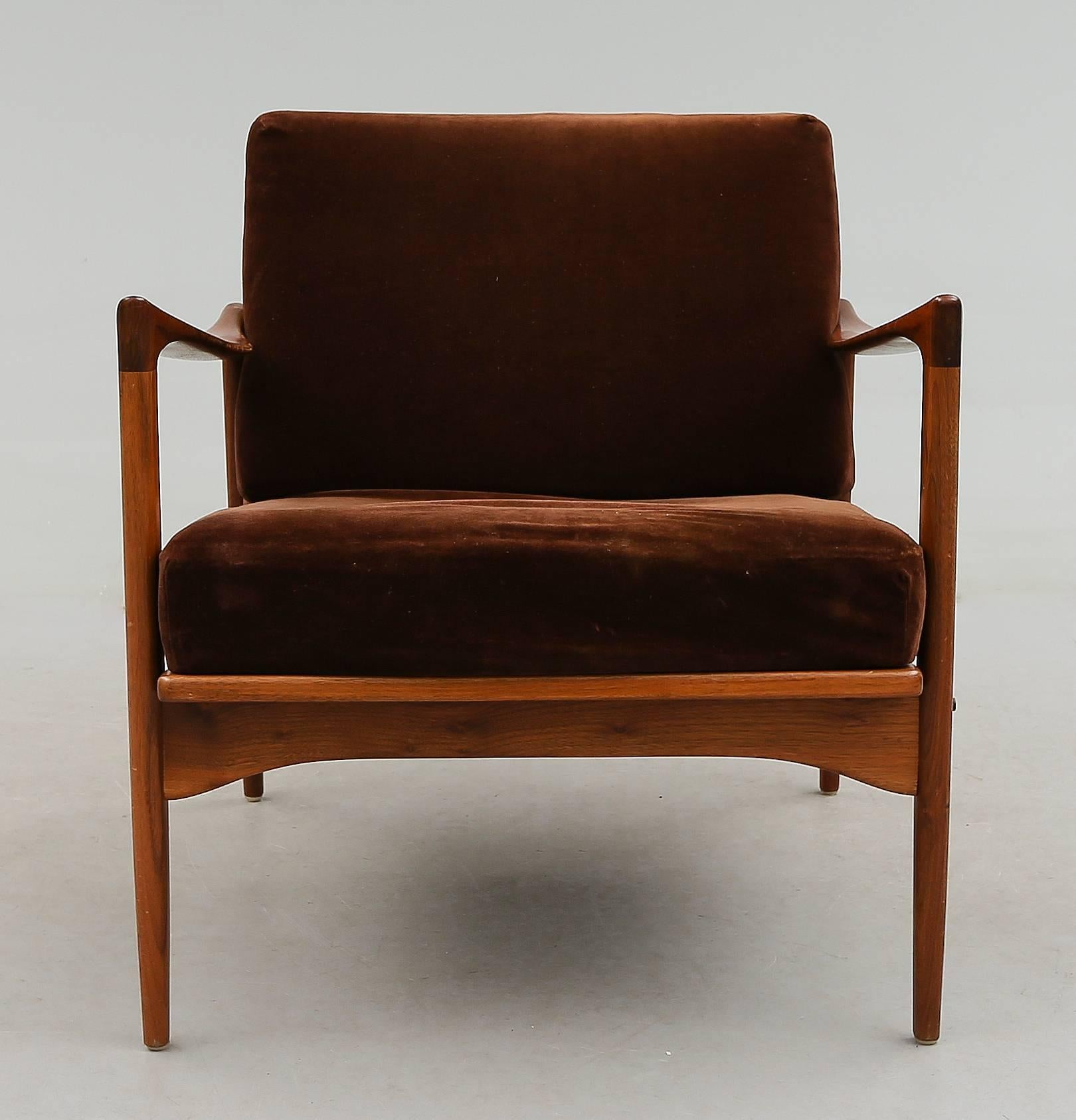 This Kandidaten easy chair was designed by Ib Kofod-Larsen and manufactured in Sweden by Olof Person in 1962.It is made from solid teak and features cylindrical tapered legs with long bowed armrests. In a very good vintage condition.